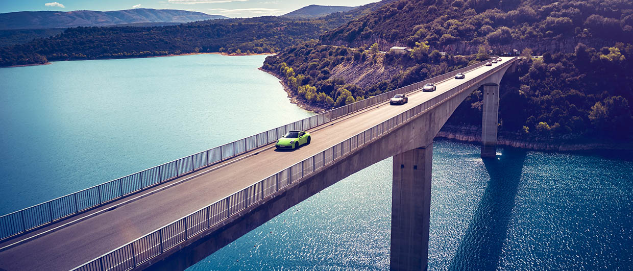 Porsche 911 is driving on a bridge over a sea