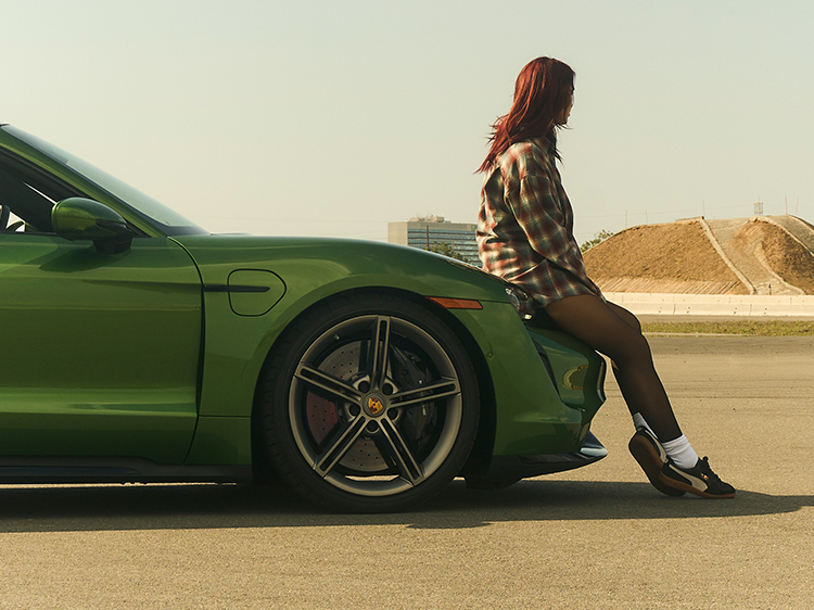 Dua Lipa sitting on bonnet of Porsche Taycan Turbo