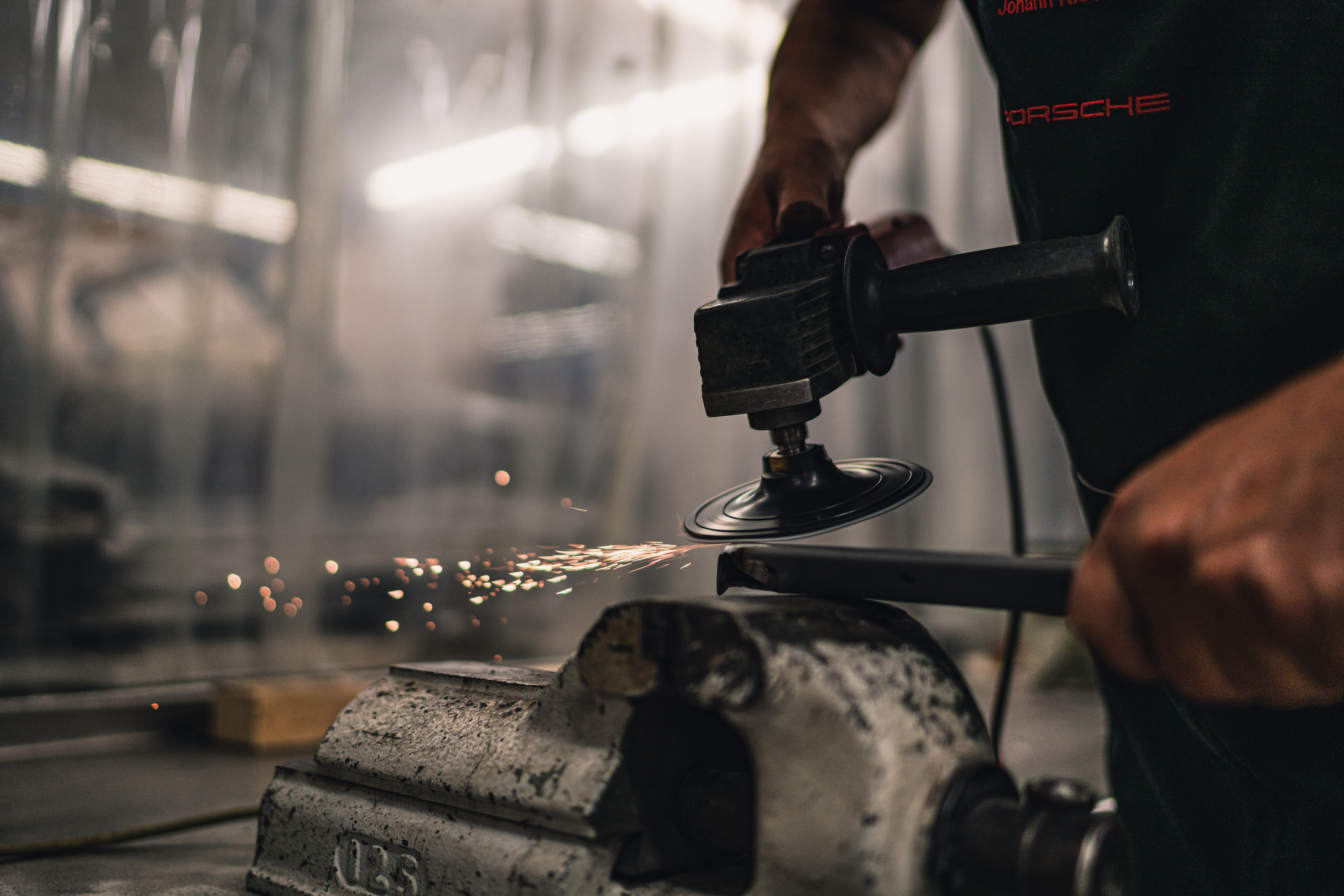 Person using angle grinder on metal bar in a workshop