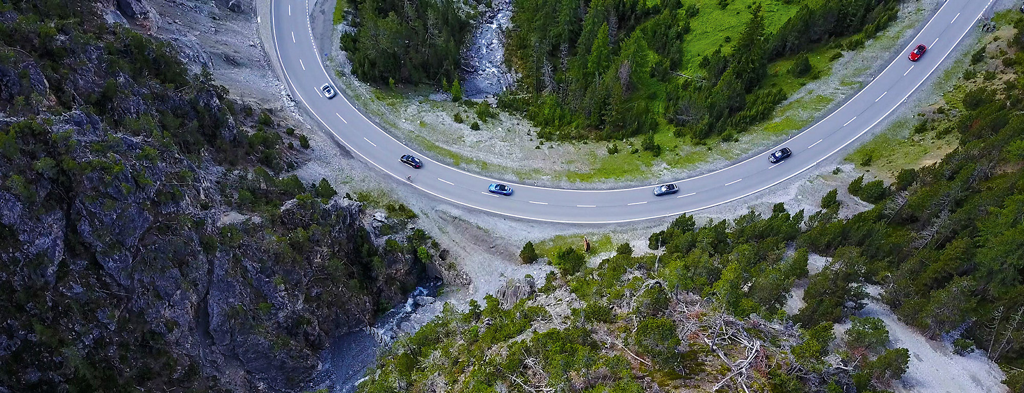 Cars drive through a sweeping bend in the mountains