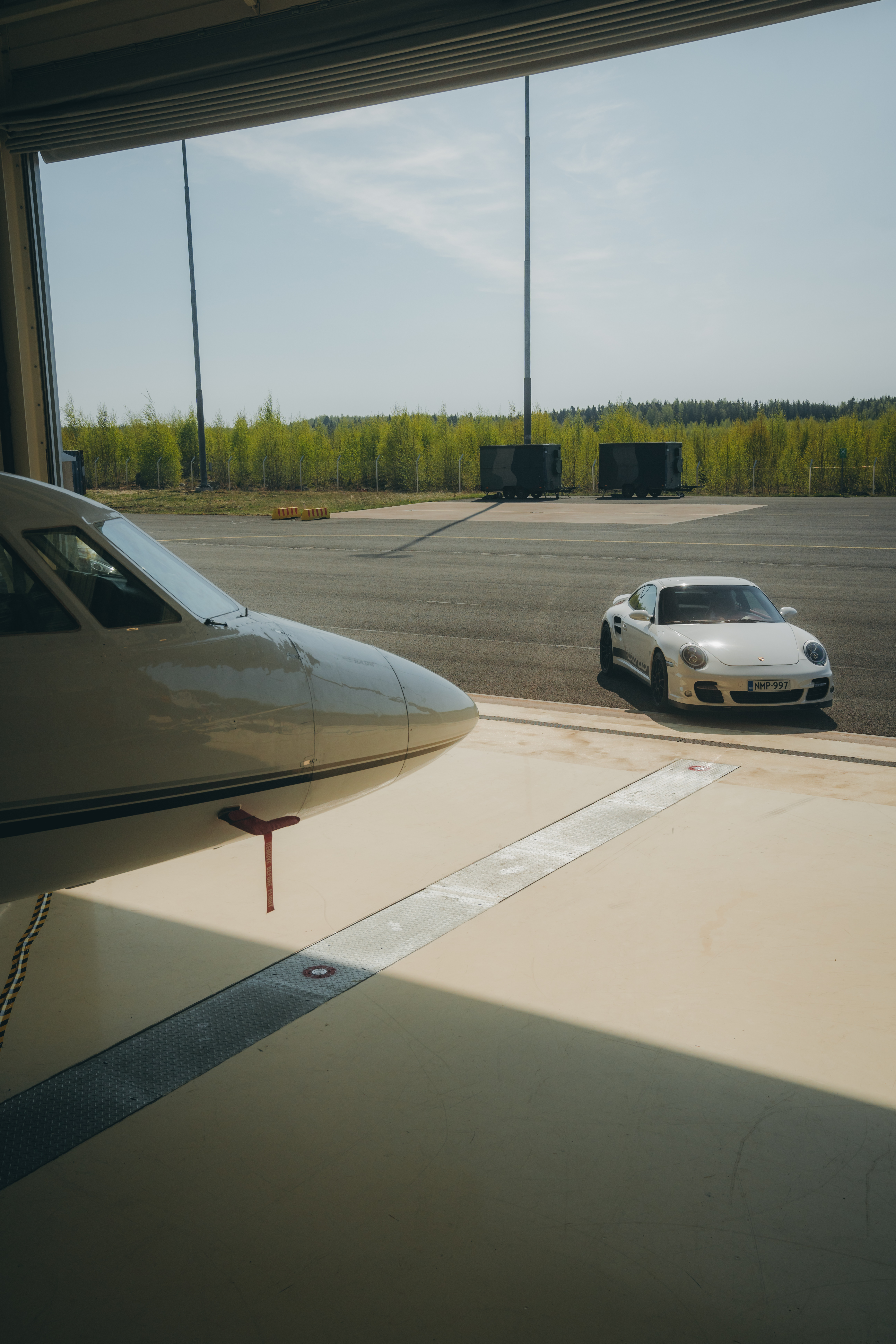 A white Porsche 911 (type 997) parked beside an airplane