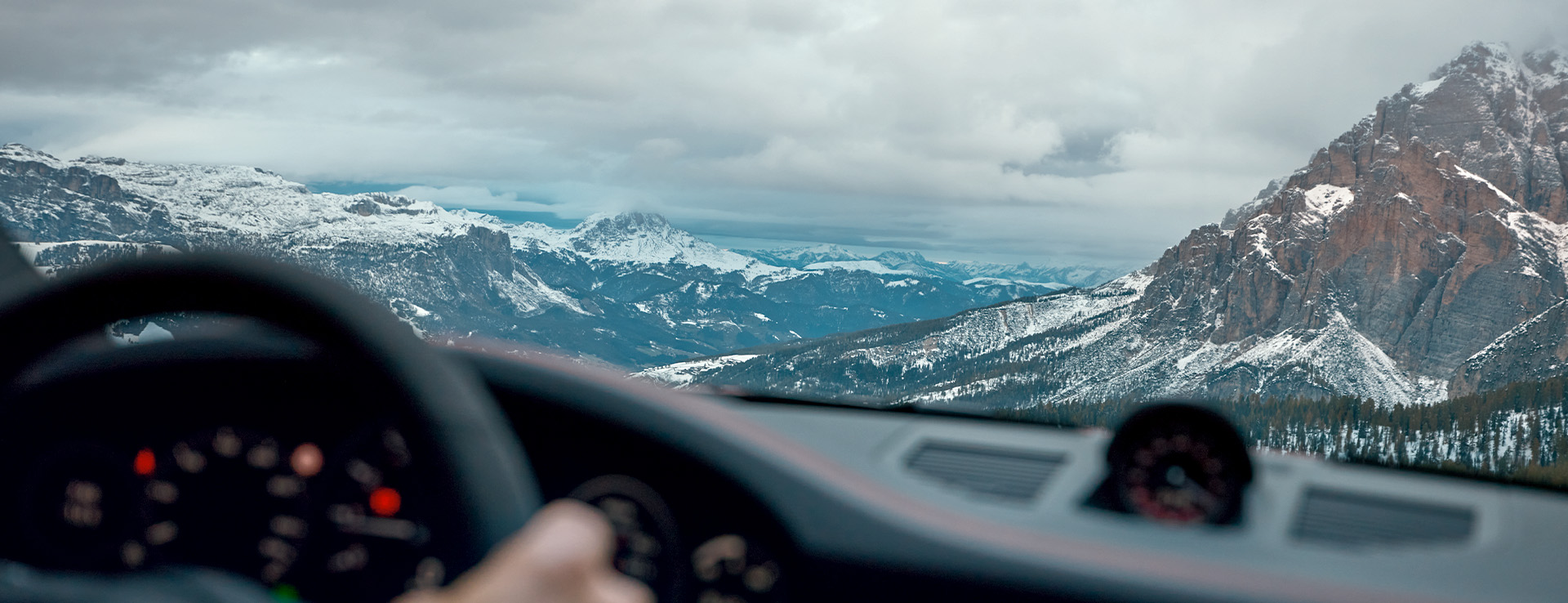 Snow-sprinkled mountains seen from driver seat of Porsche 911 GTS