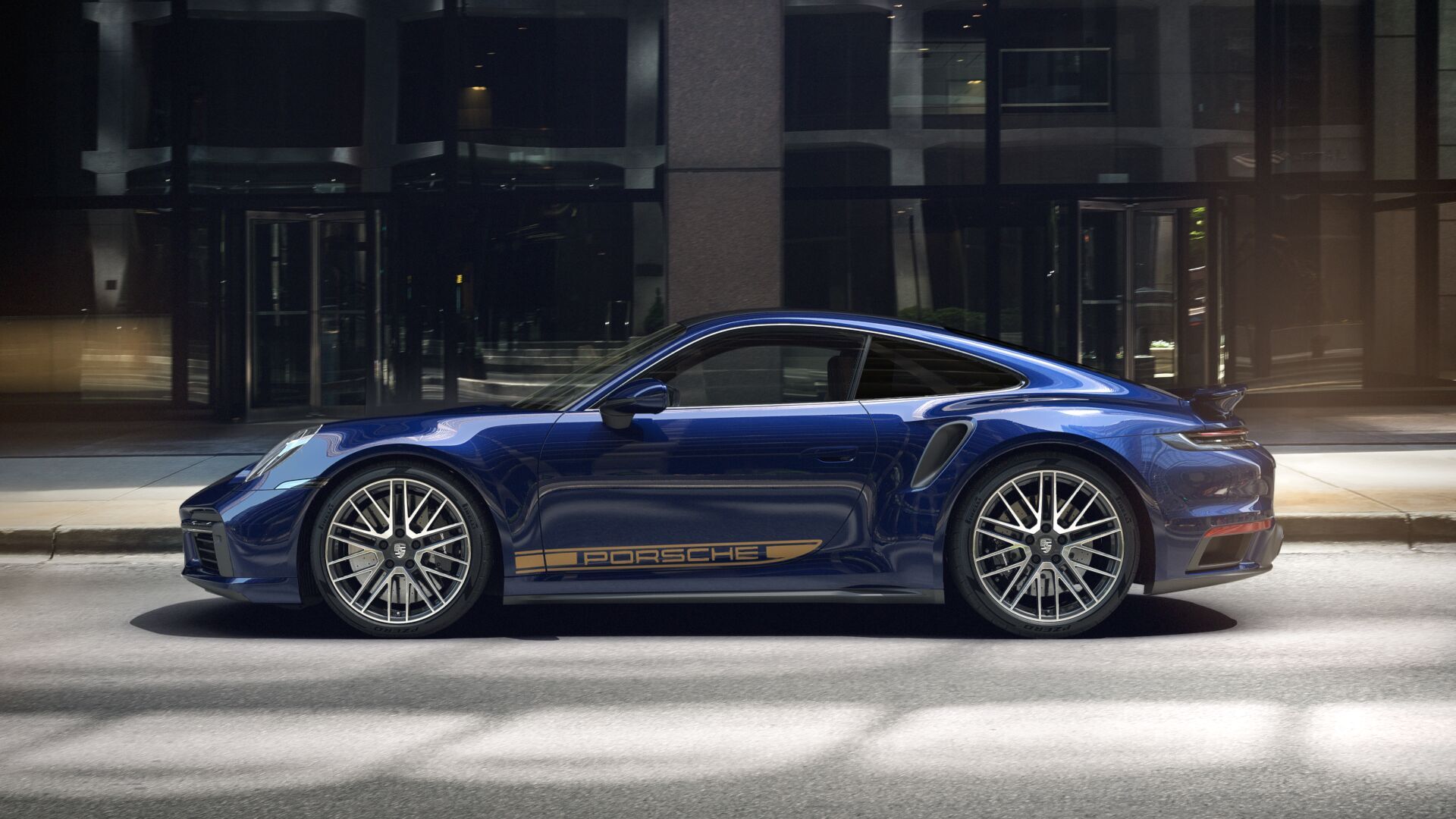Side view of blue Porsche 911 Turbo S parallel to glass-fronted building