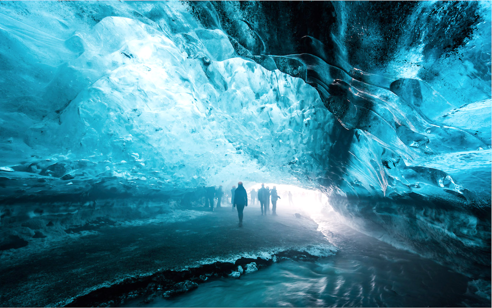 People walk through ice cave in blue light