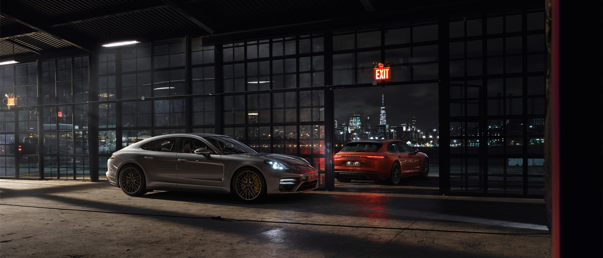 Two Panamera Sport Turismos parked inside and outside warehouse at night