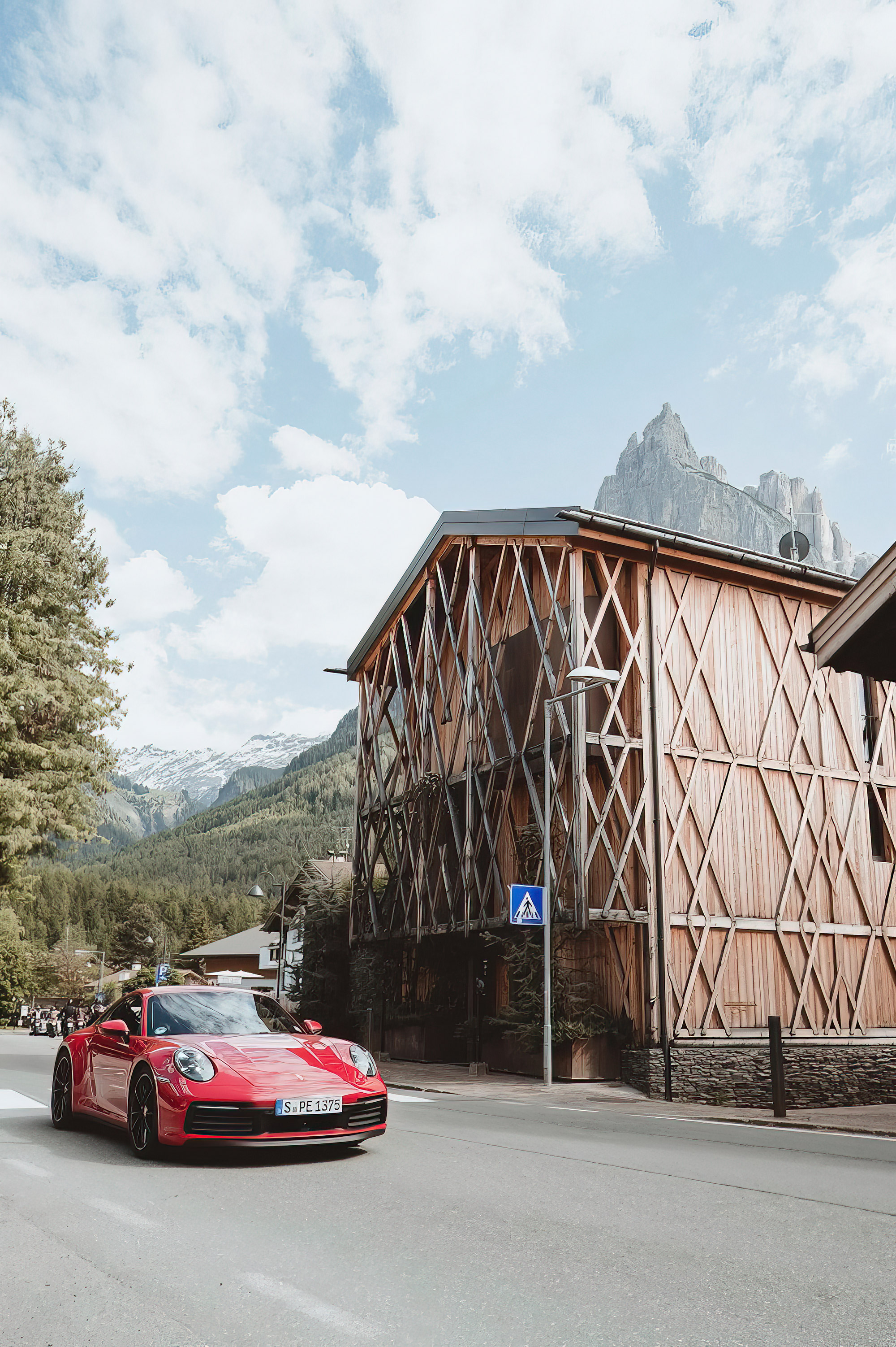 Red Porsche 911 drives past house with wood panelling