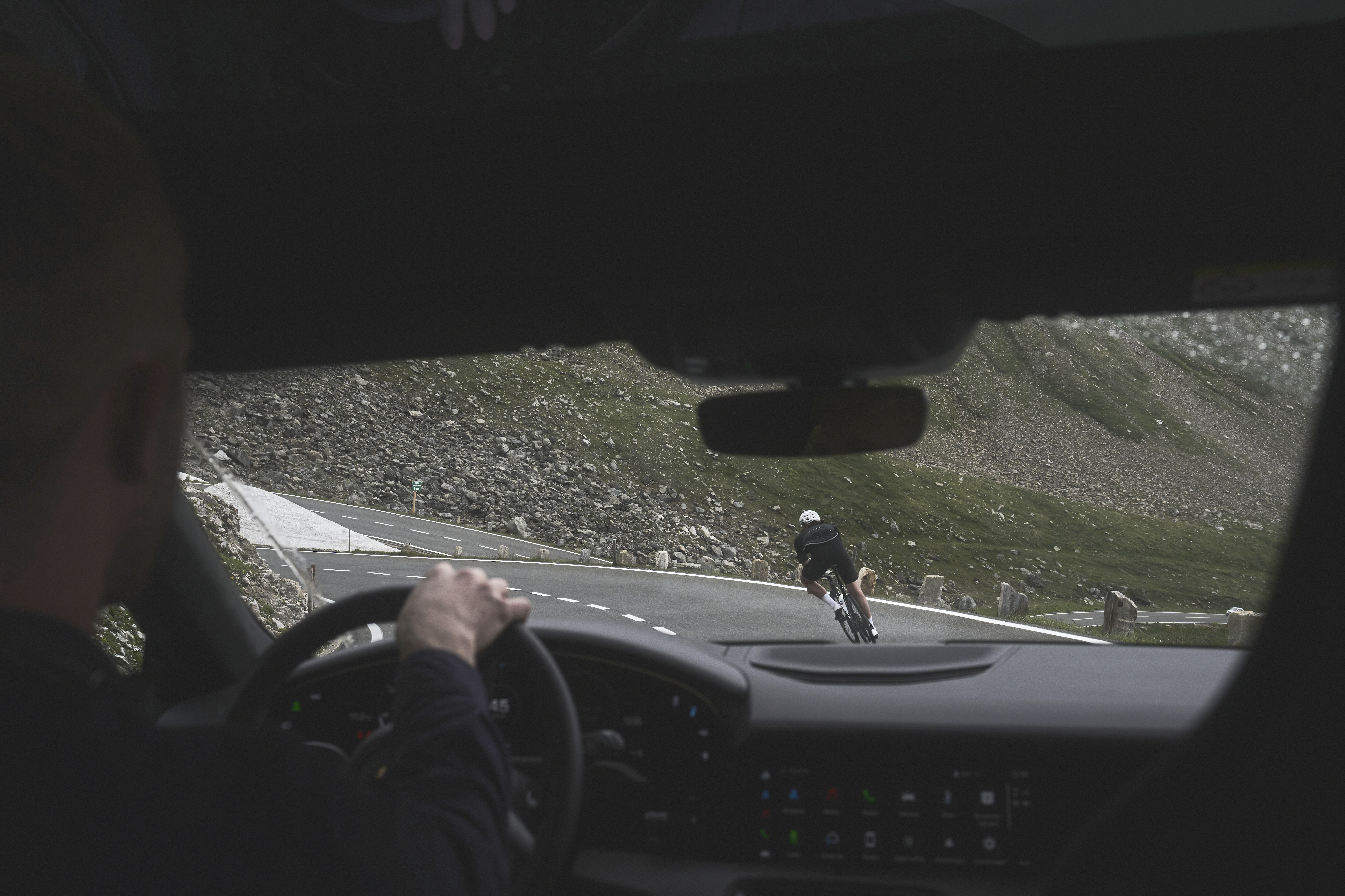 View from inside a car as cyclist corners mountain bend