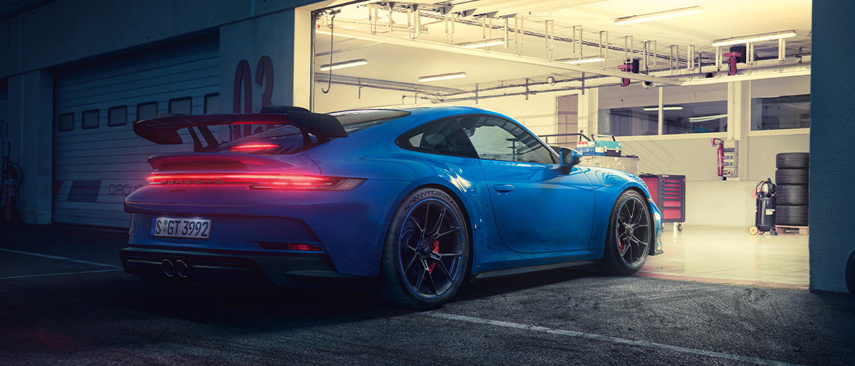 Blue Porsche 911 GT3 with lights on apex of racetrack