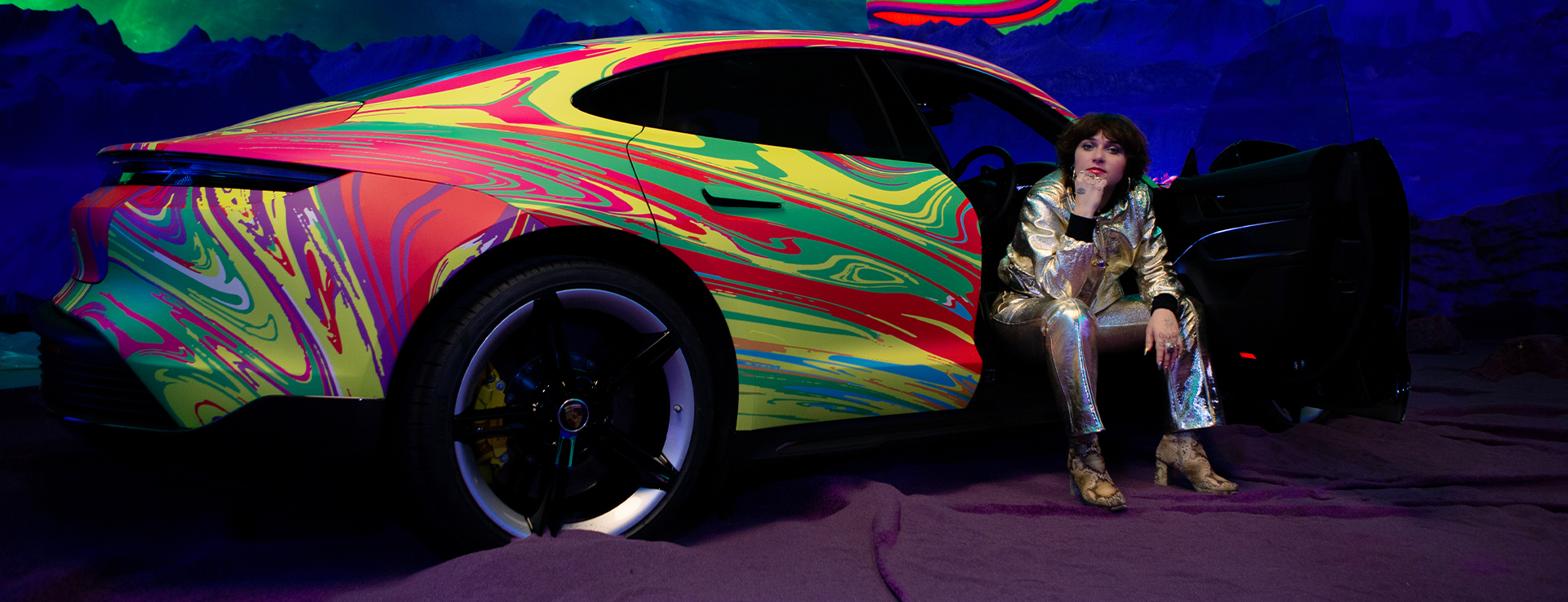 Woman in lamé suit with electric Porsche Taycan art car