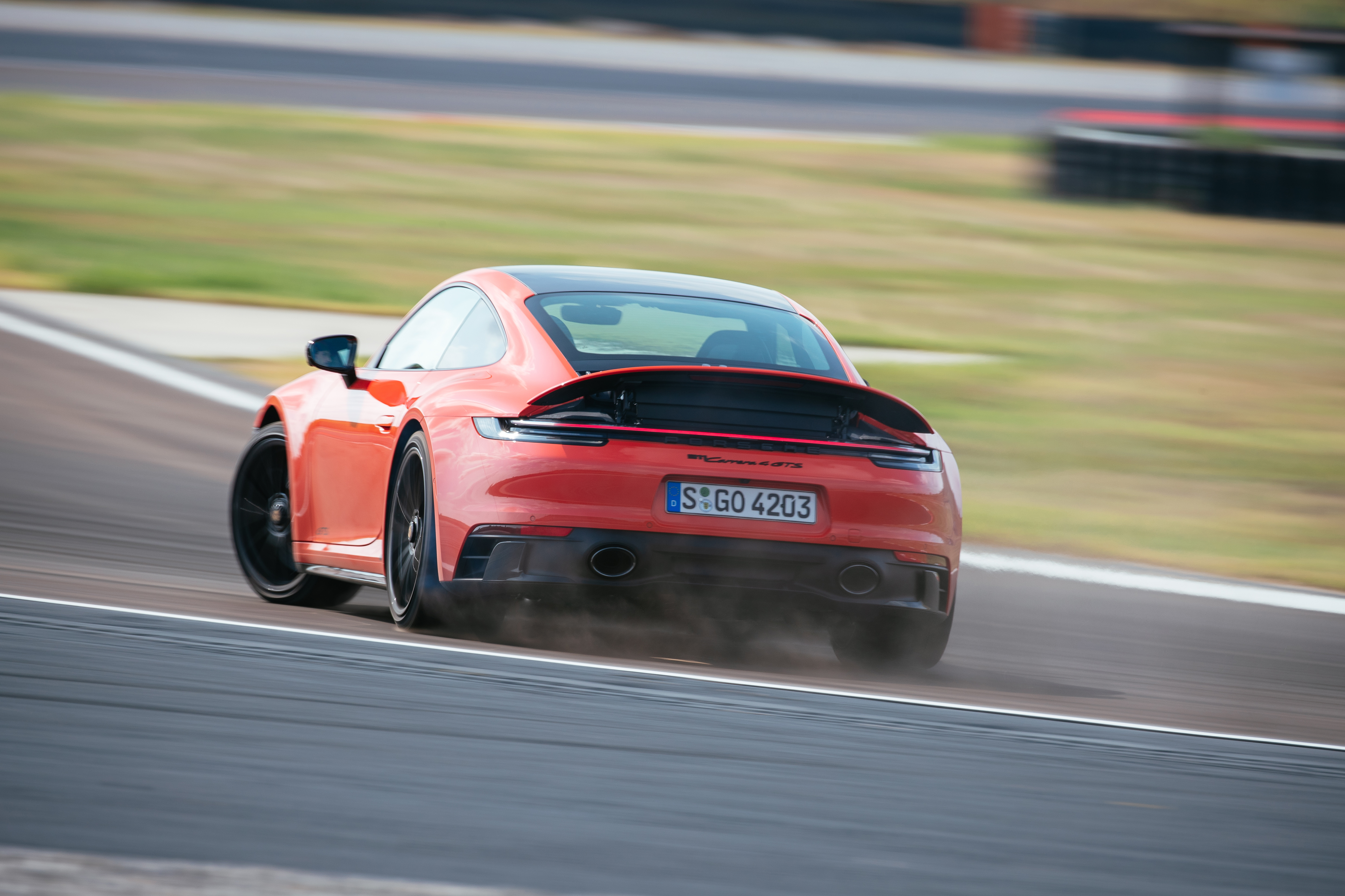 Orange Porsche 911 Carrera 4 GTS sliding on a track