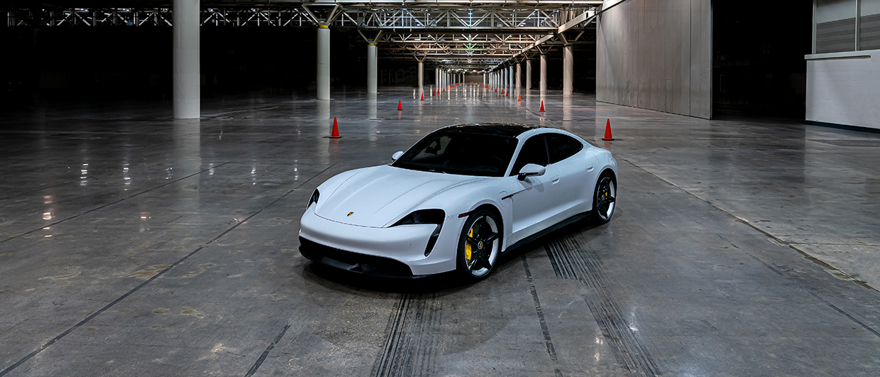 White Taycan Turbo S in large, empty exhibition hall