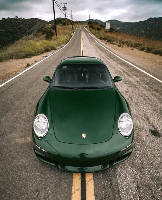 Dark green Porsche 911 (type 997.1) straddling centre of road