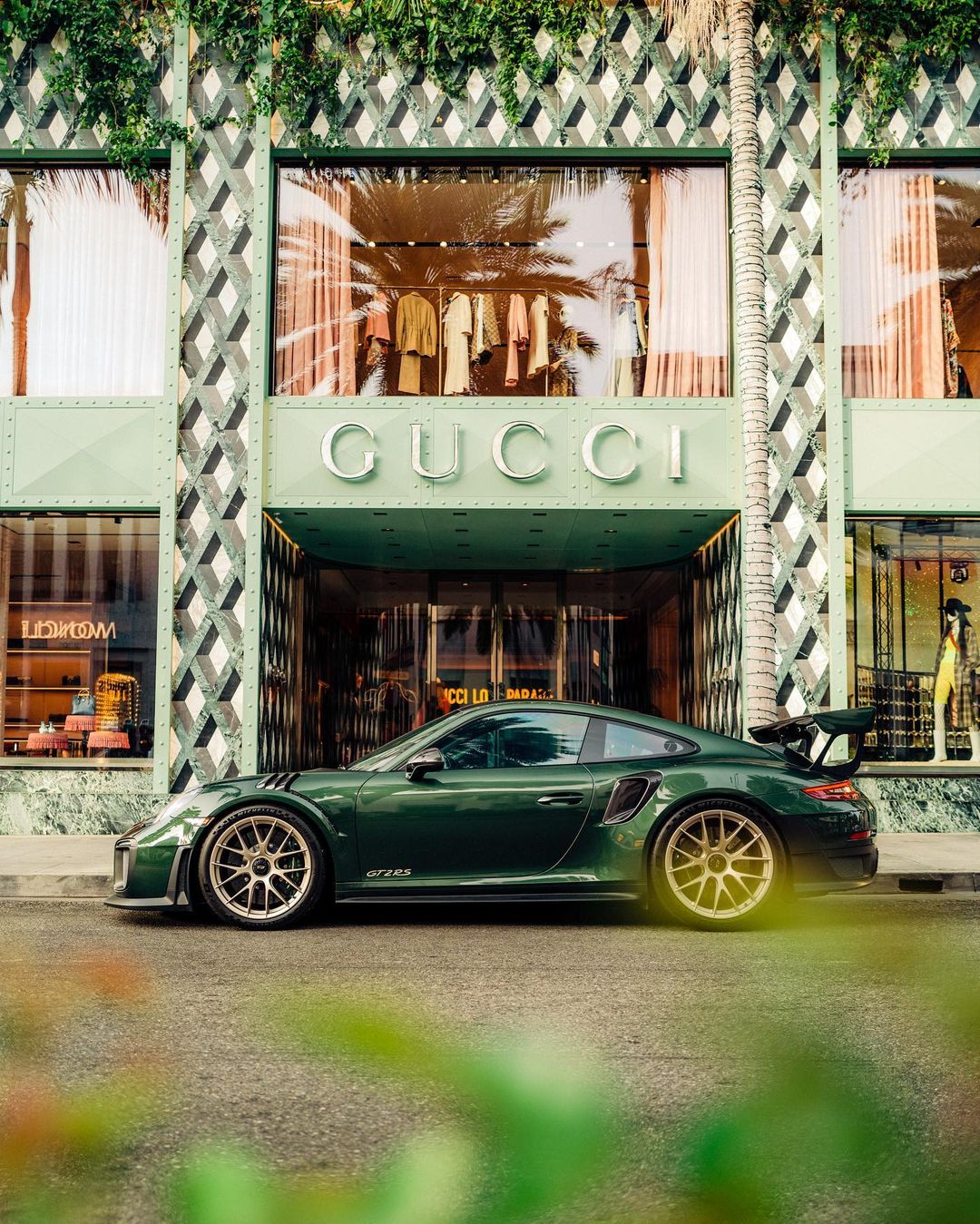 Green 911 parked in front of a green Gucci storefront