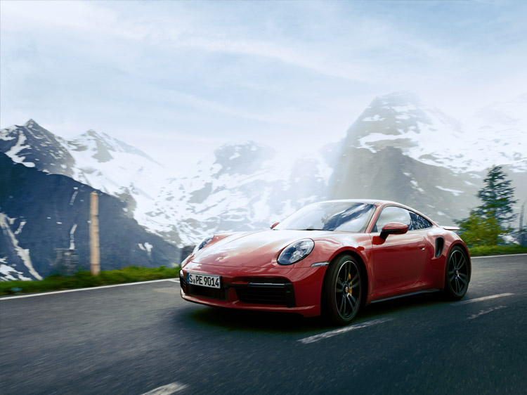 Porsche 911 turbo s driving in front of a mountain range