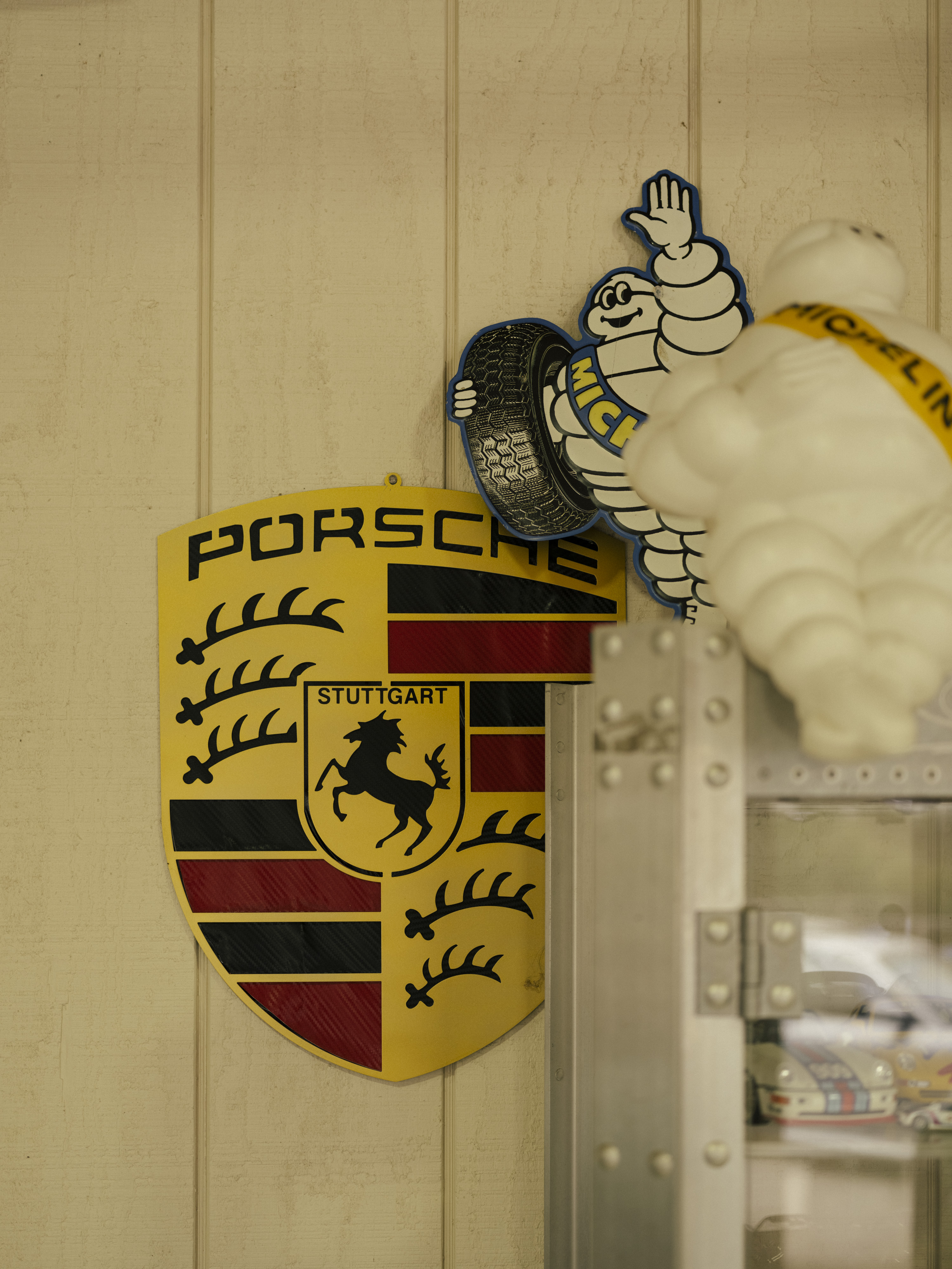 Large Porsche logo on wall, alongside two Michelin men