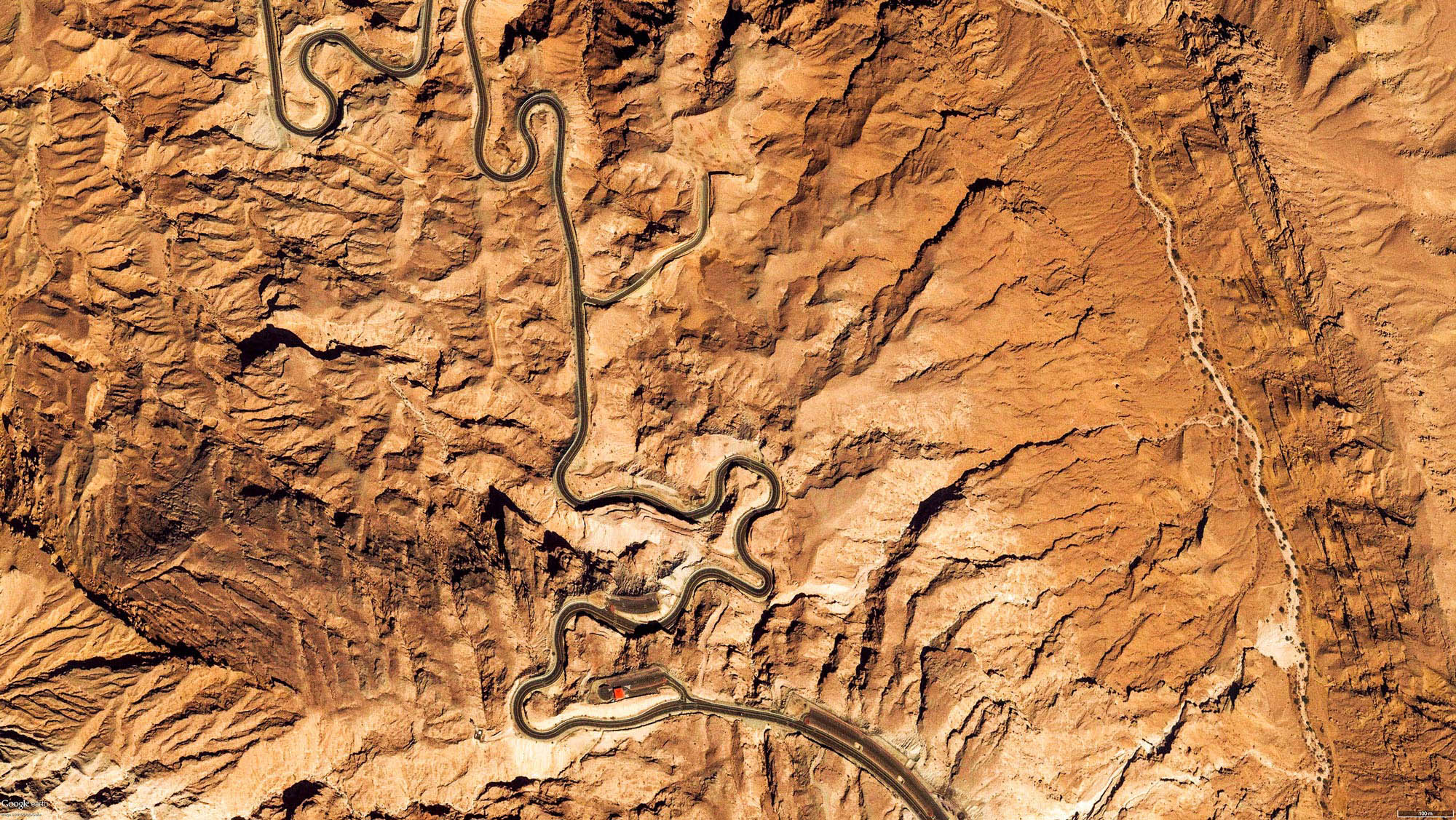 Aerial view of winding road across rocky desert mountains