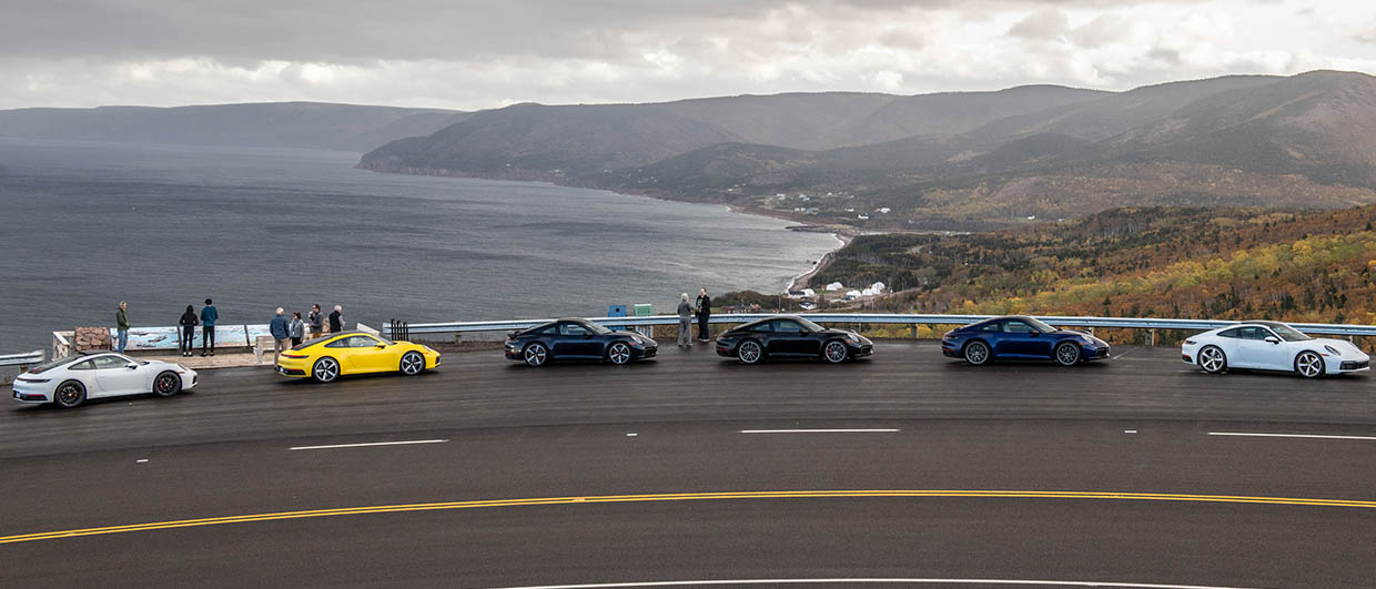 Four Porsche standing in front of the sea on a cloudy day