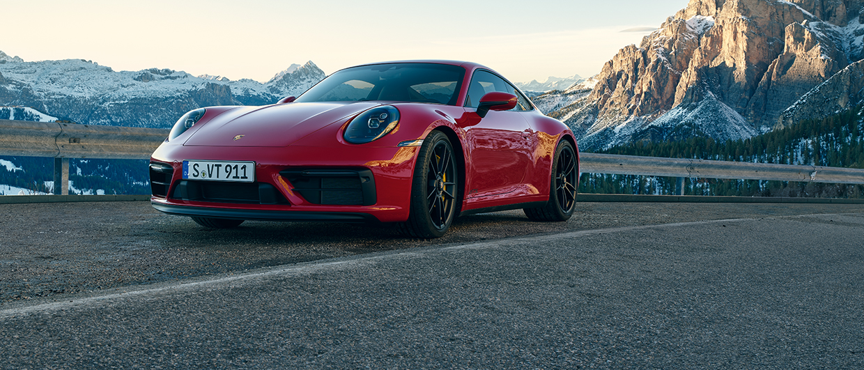 Red Porsche 911 GTS against snowy mountain backdrop