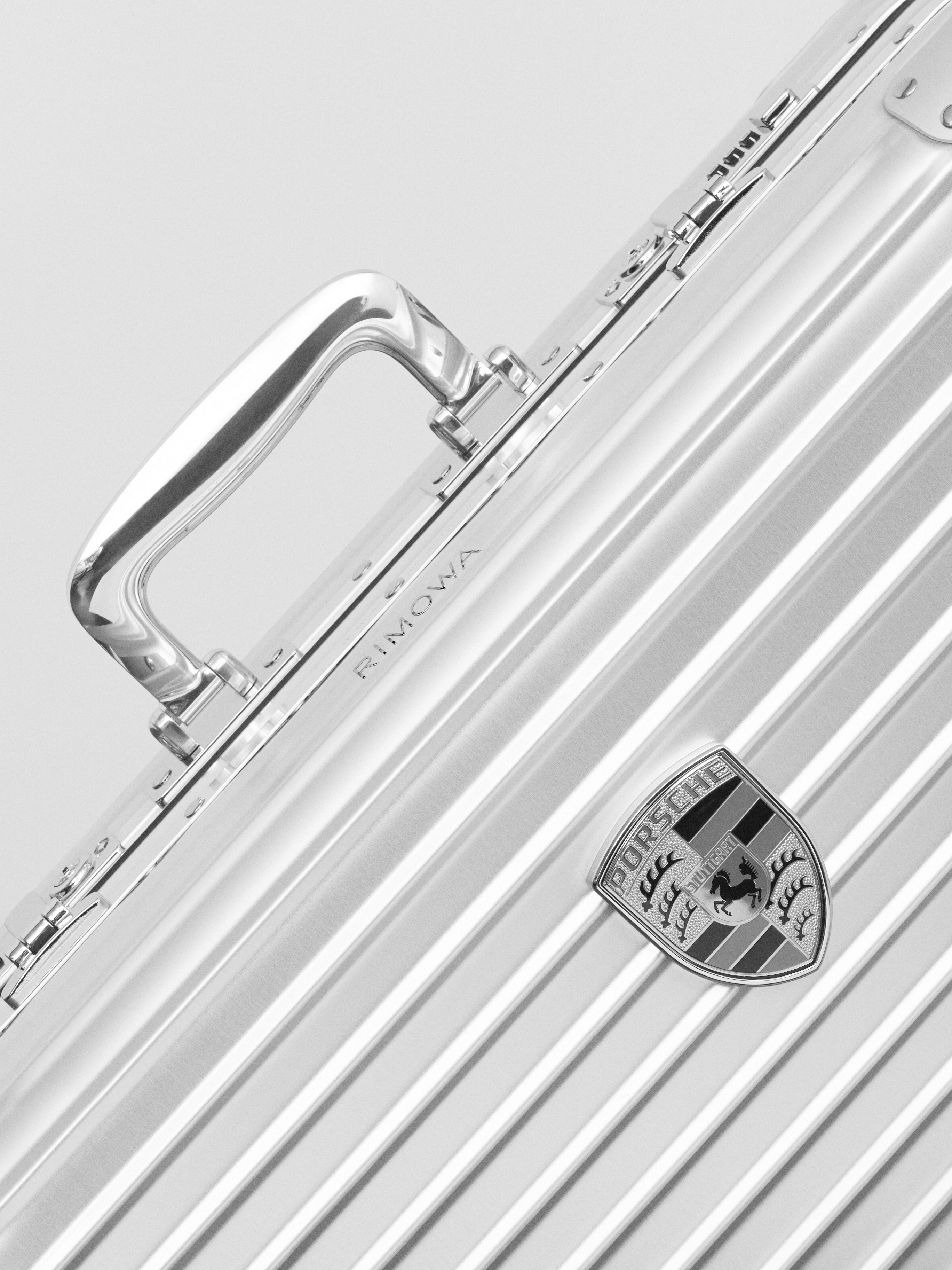 Close-up of metal RIMOWA suitcase with Porsche badge on front