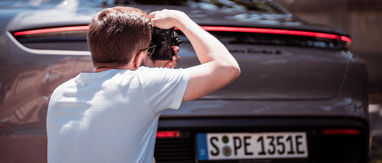 Man with camera taking photographs of Porsche Taycan