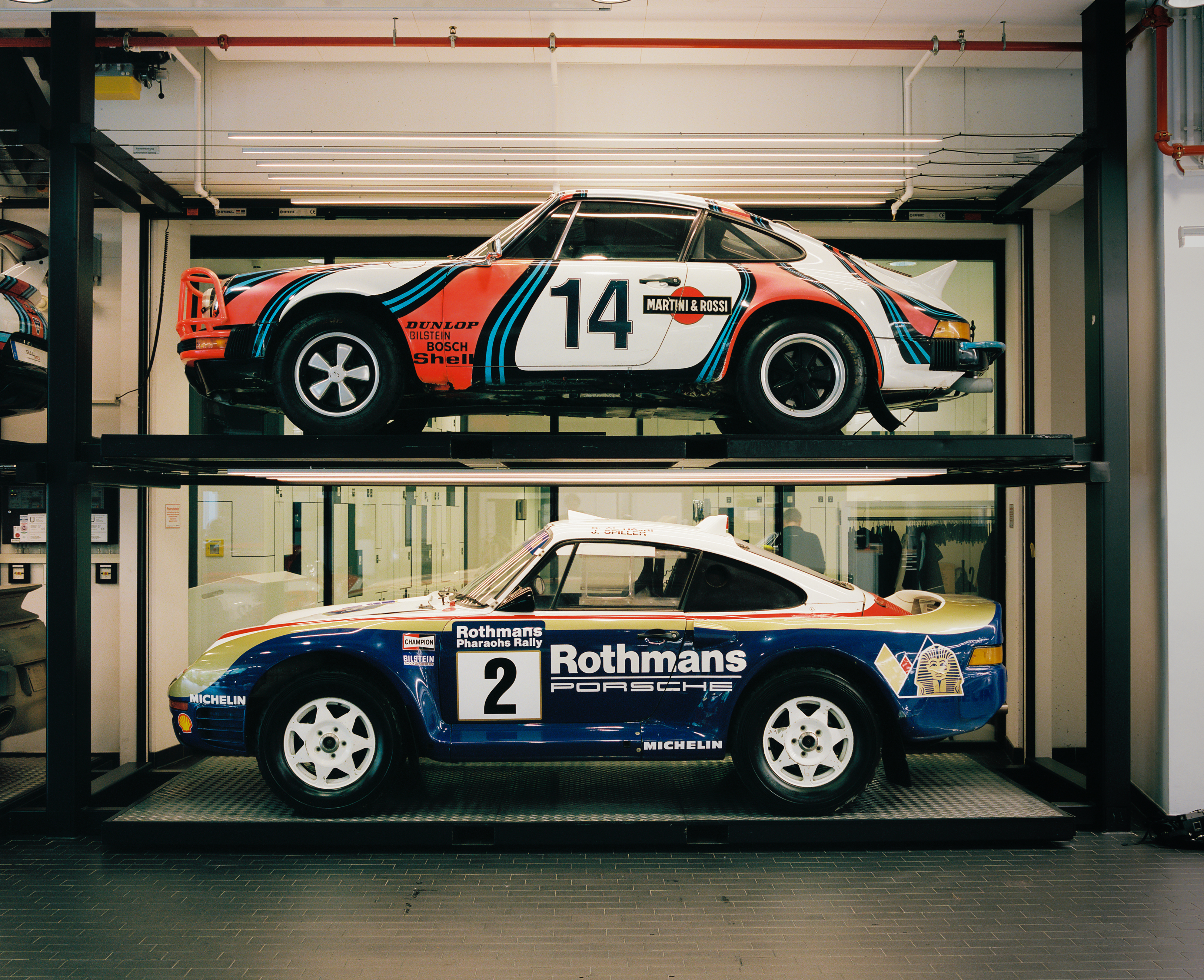 Porsche racecars in racing livery in the Porsche Museum workshop
