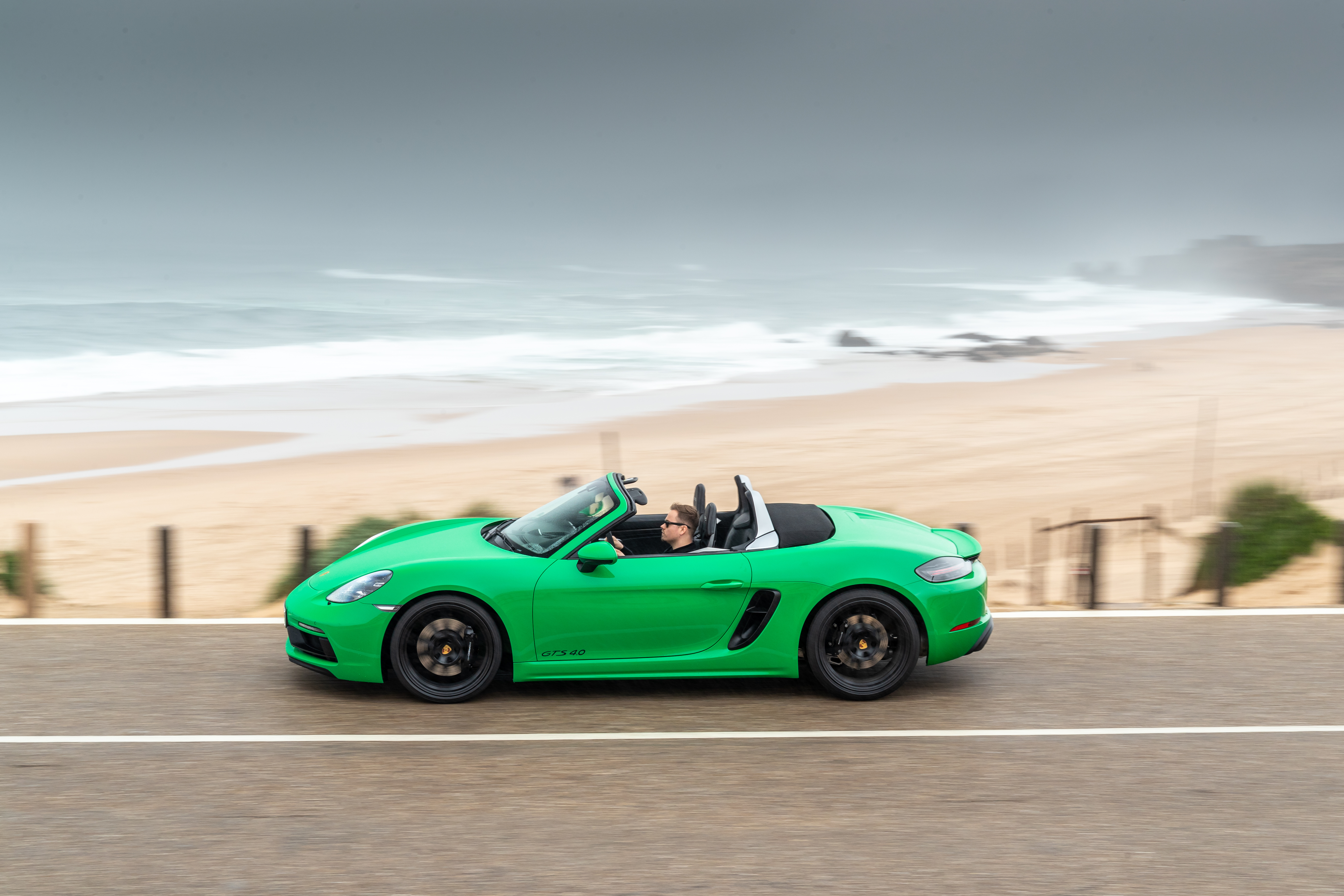 Green new 718 Boxster GTS 4.0 drives past stormy beach
