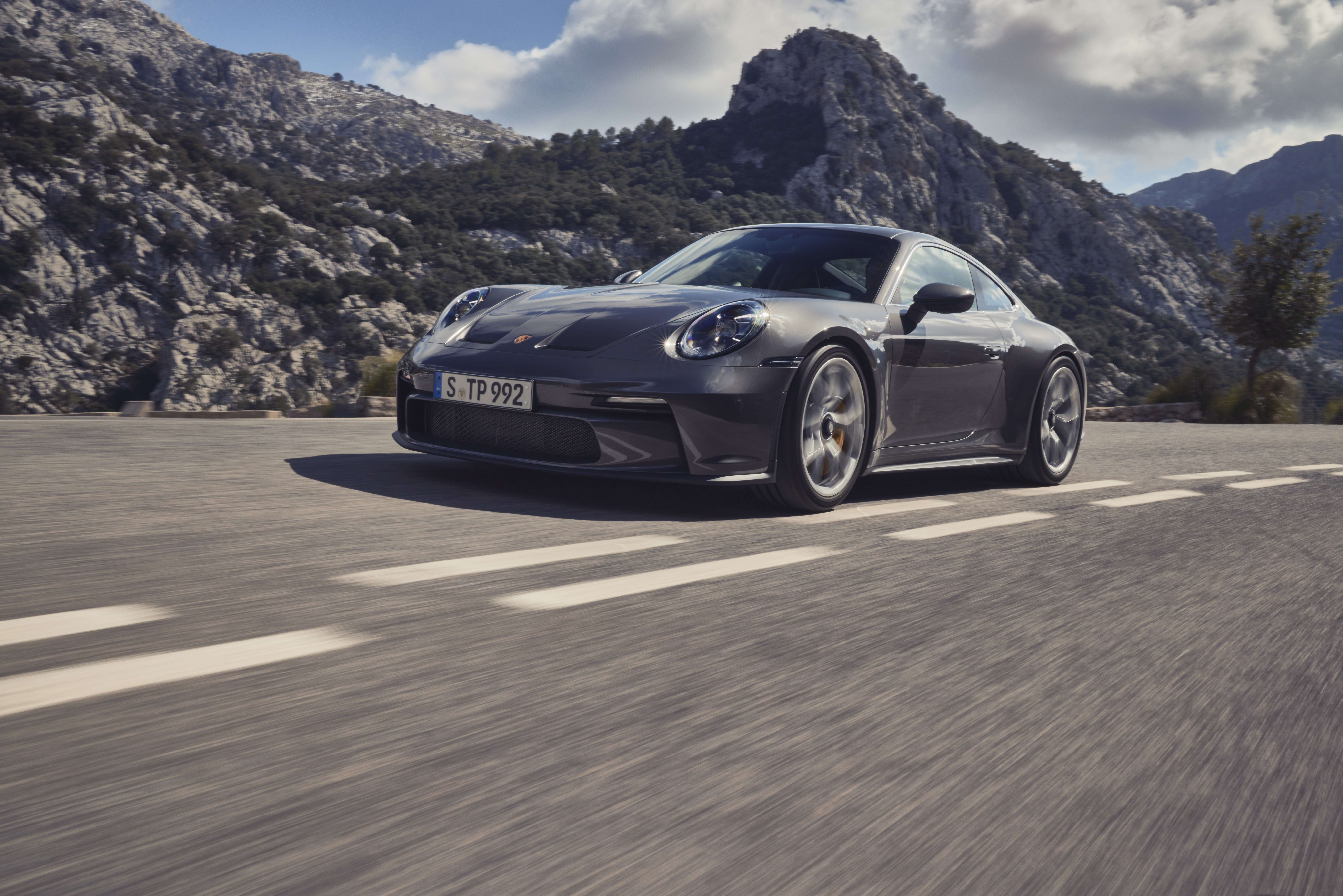 Dark grey 911 GT3 with Touring Package on roads, mountains behind