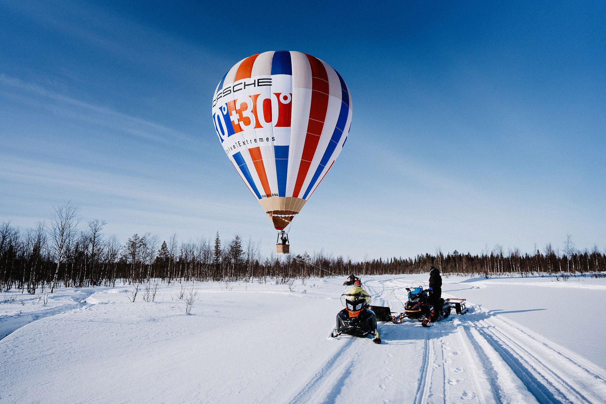 A hot air balloon and two snowmobiles in the Finnish landscape