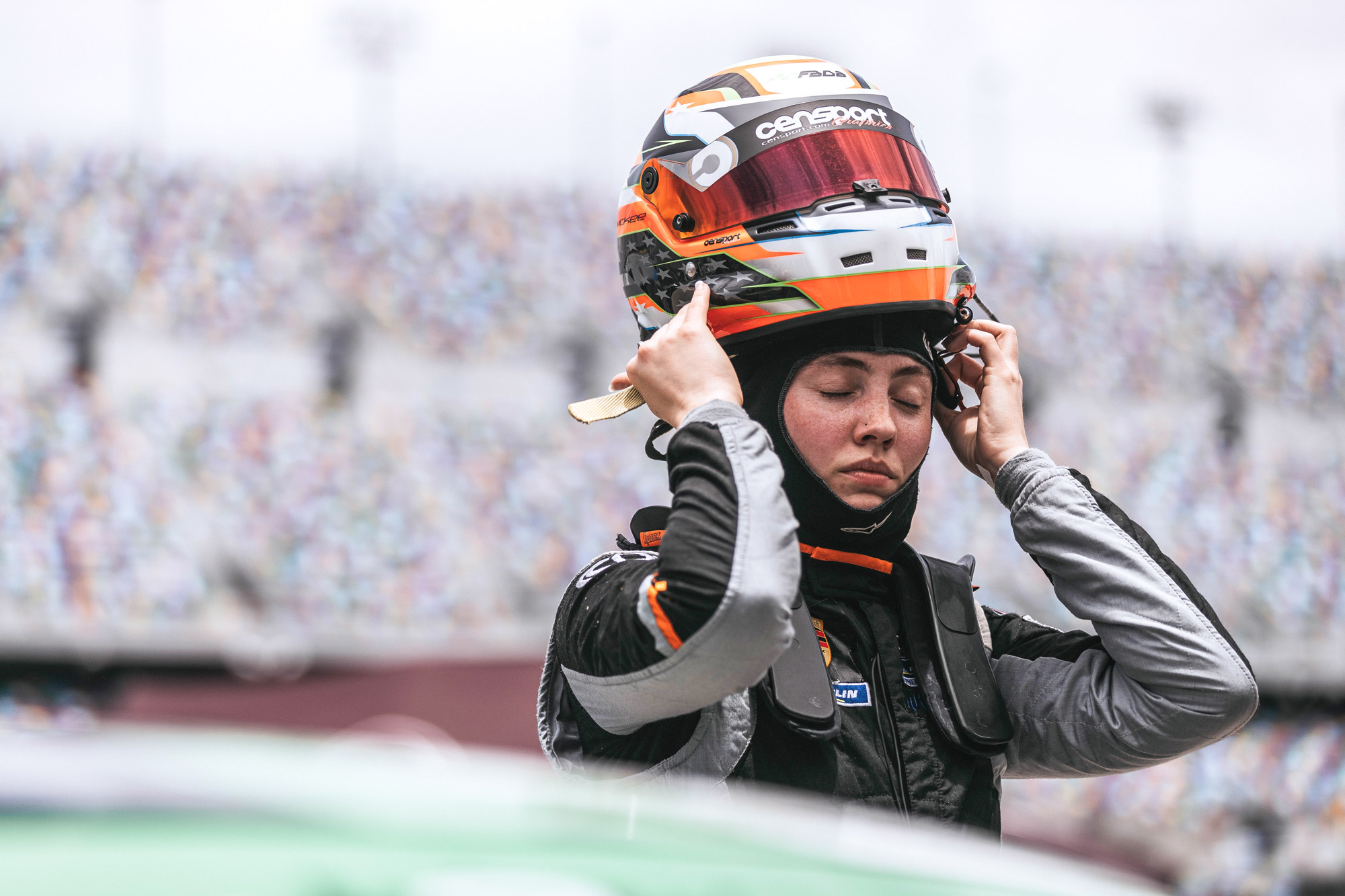 A woman puts on a racing helmet