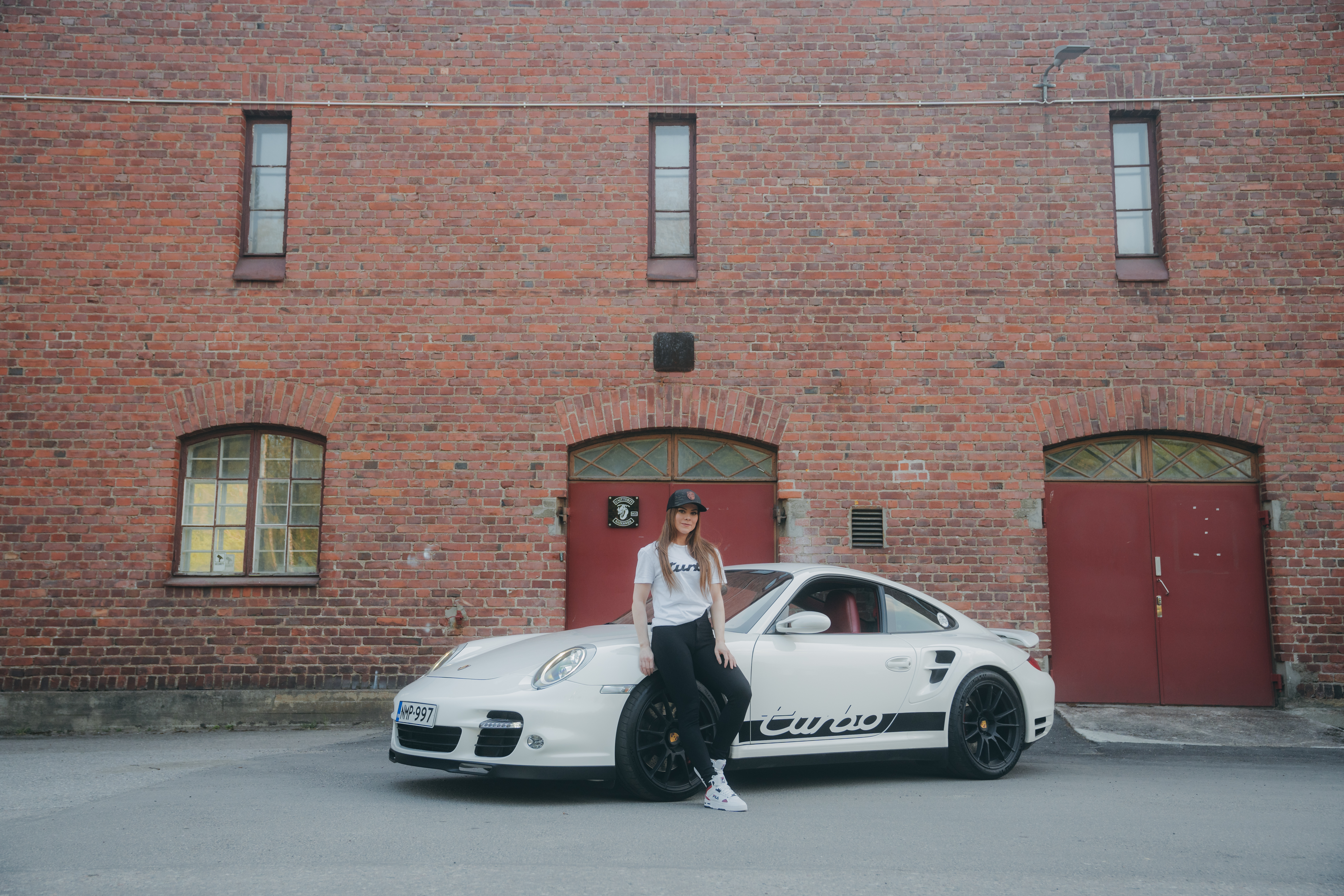 Woman standing beside a white Porsche 911 Turbo (type 997)