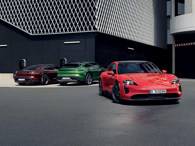 Three Porsche Taycan models parked next to modern building