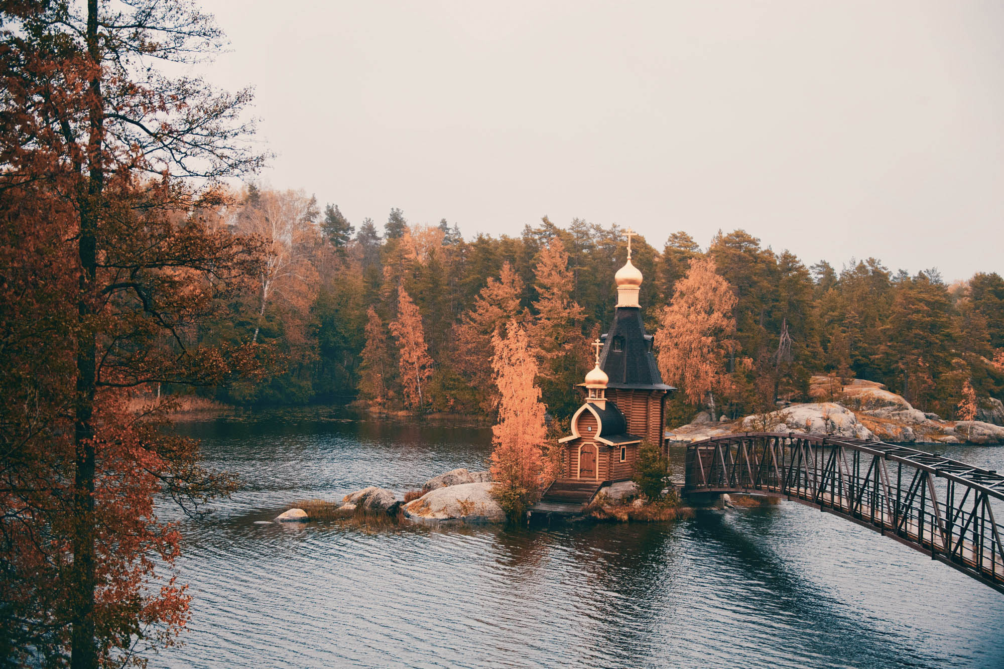 Wooden church in middle of lake, bridge leading to it