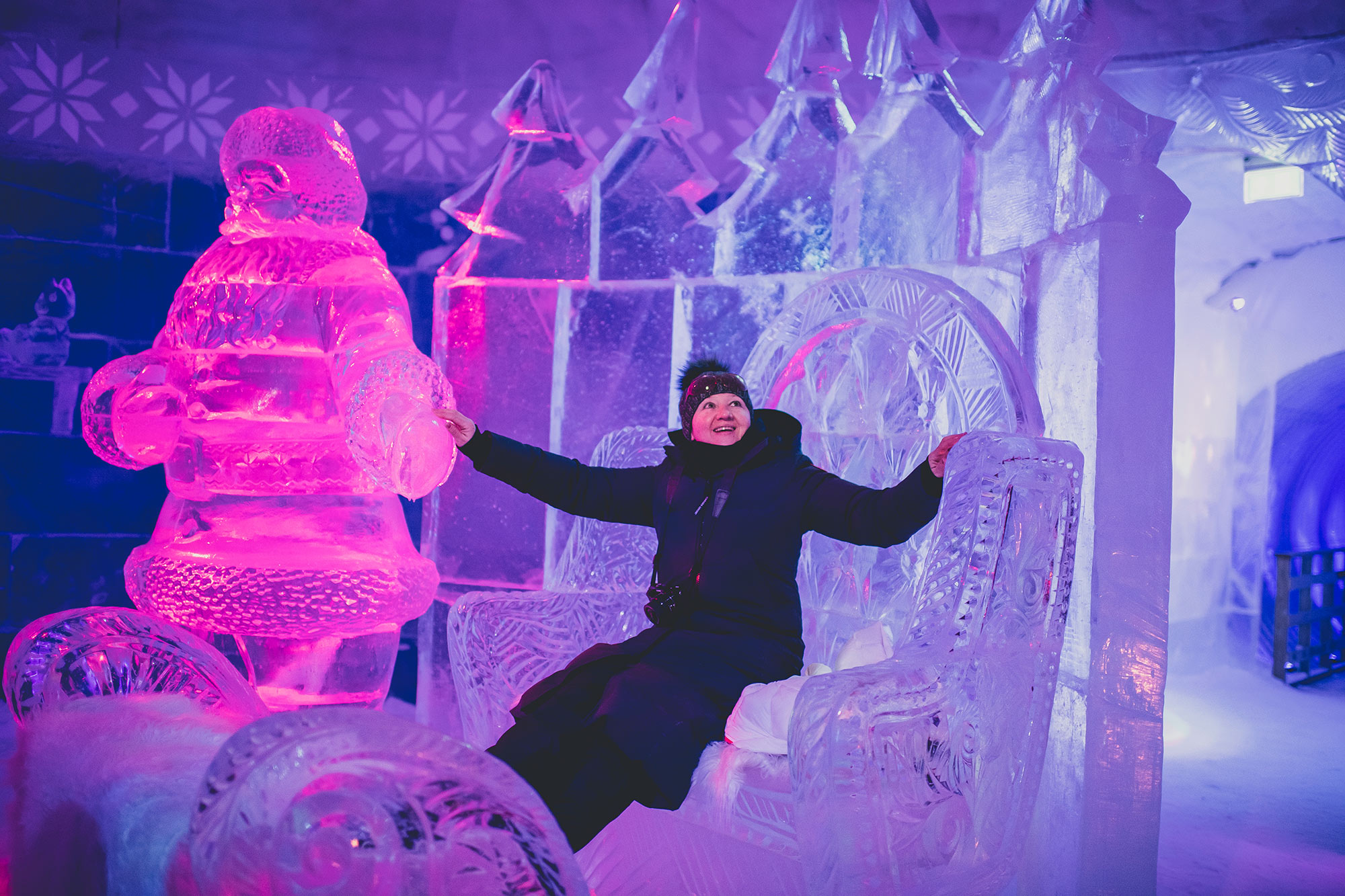 Woman sits on giant ice throne within ice hotel