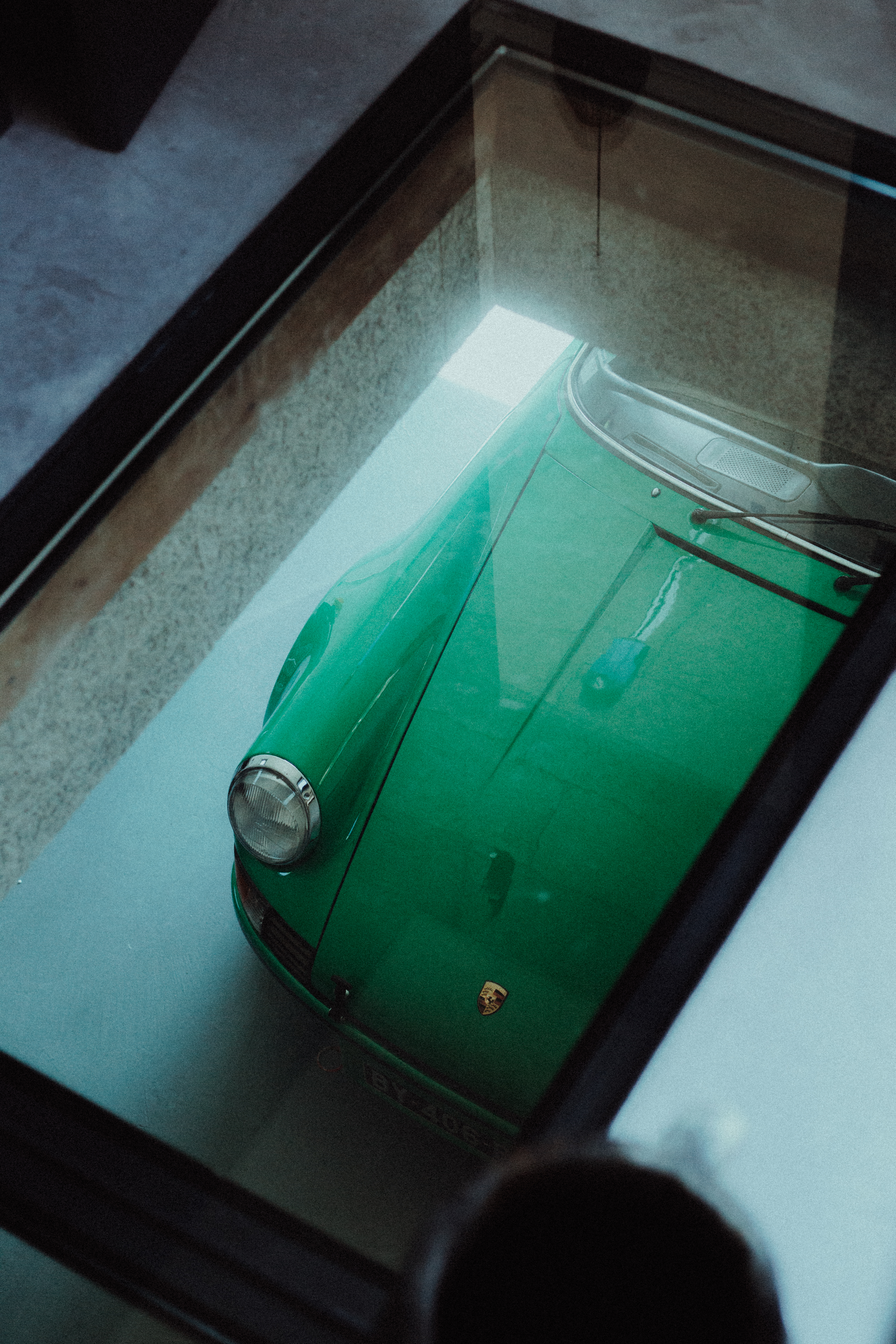 Green Porsche 911 seen through glass floor of a living room