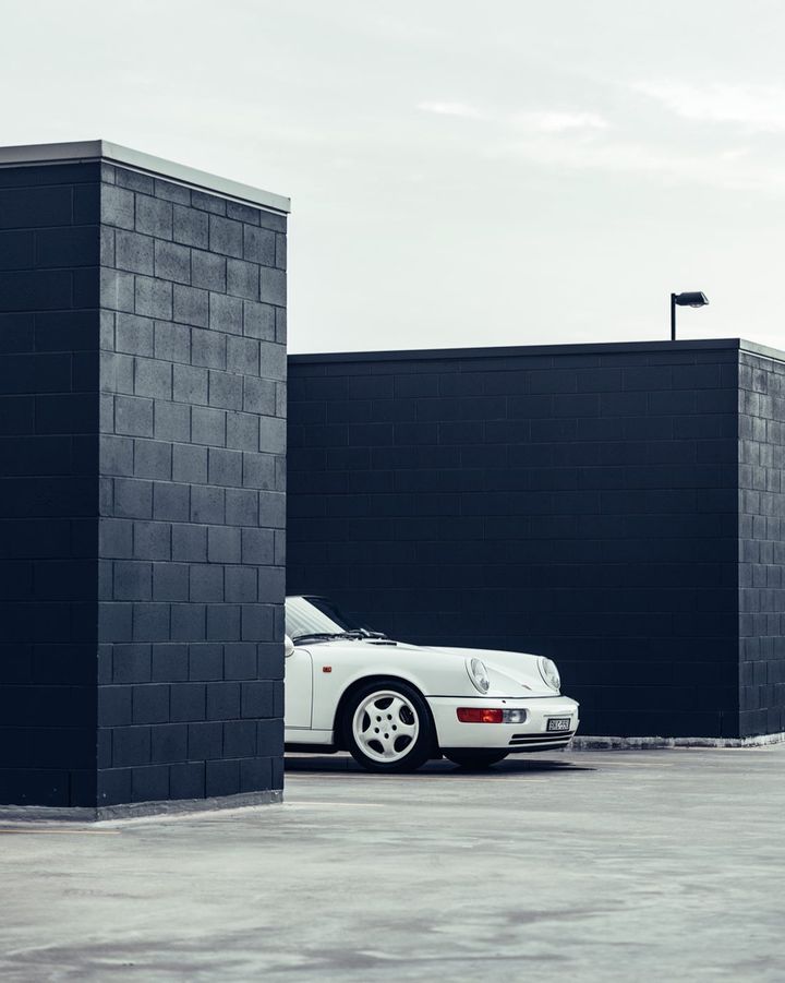 A white Porsche 911 between two black brick blocks