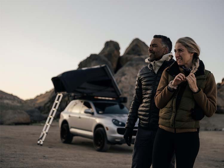 Couple in front of Porsche Cayenne with tent
