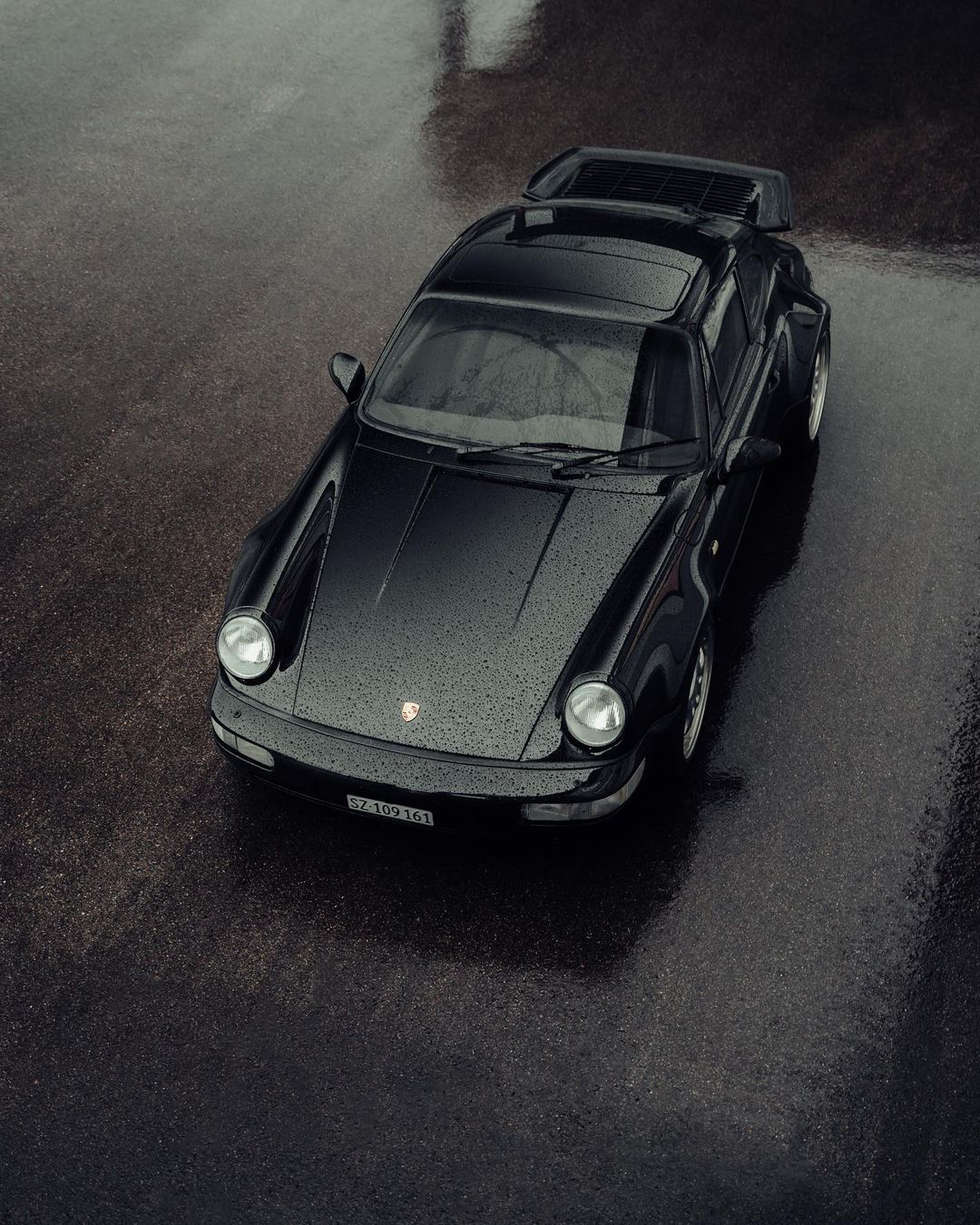 Black Porsche 911 (type 964) on wet road, from above
