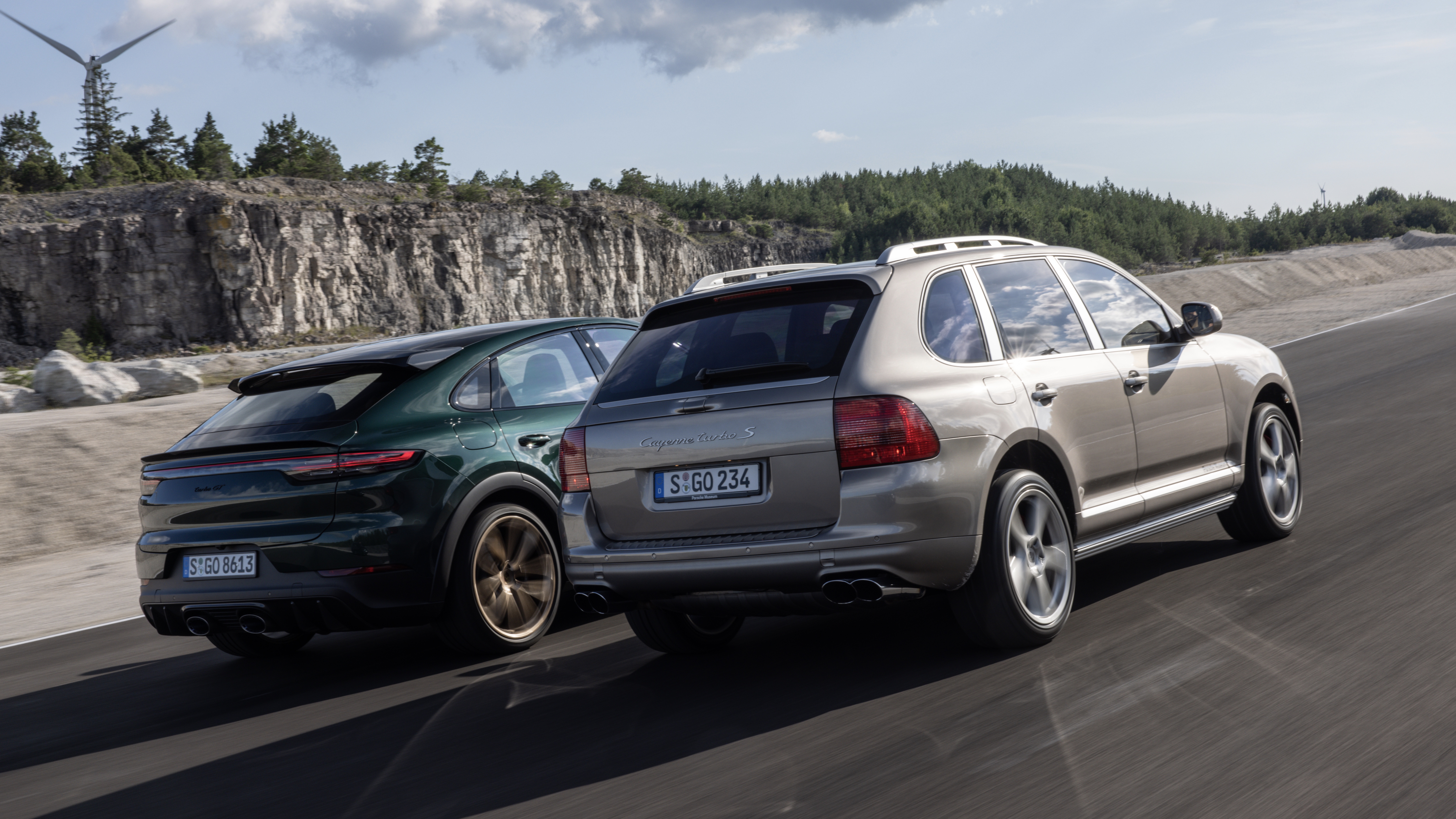 Two Porsche Cayenne SUVs driving side by side on road 