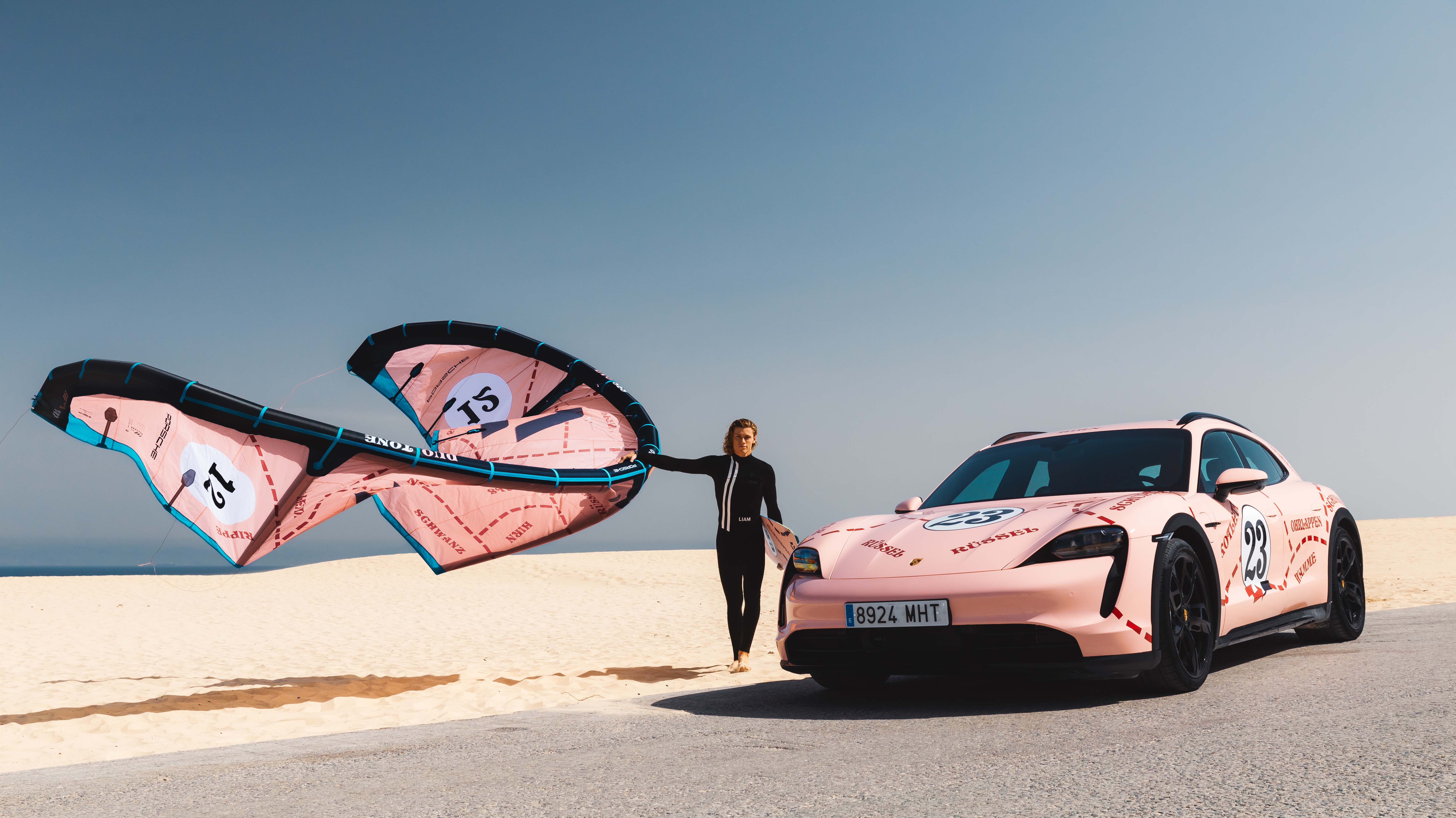 Kitesurfer with kitesail on beach with Porsche Taycan Cross Turismo