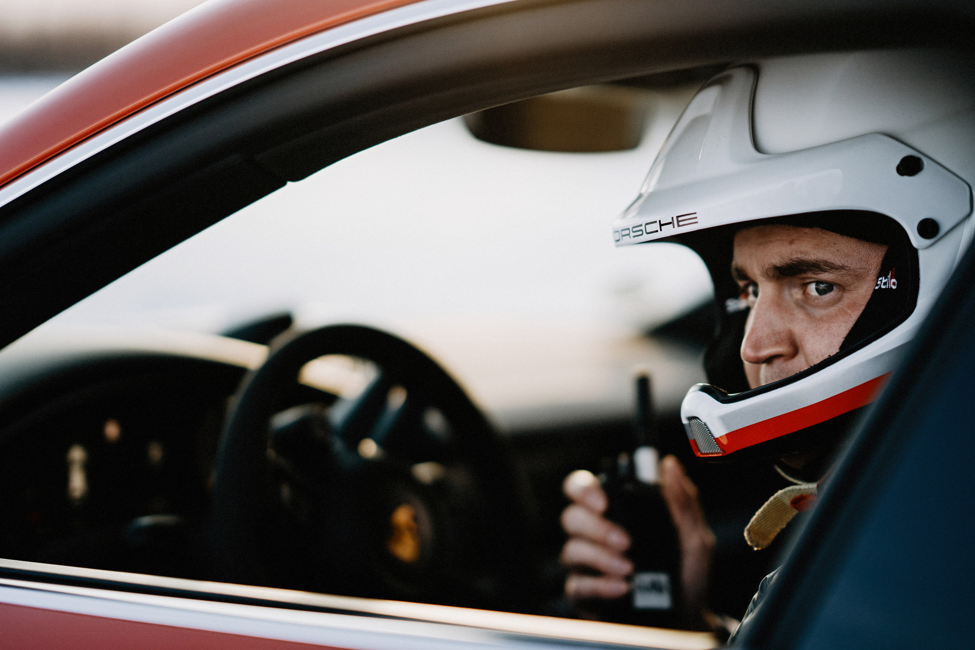 Driver wearing helmet behind wheel of Porsche Taycan Cross Turismo