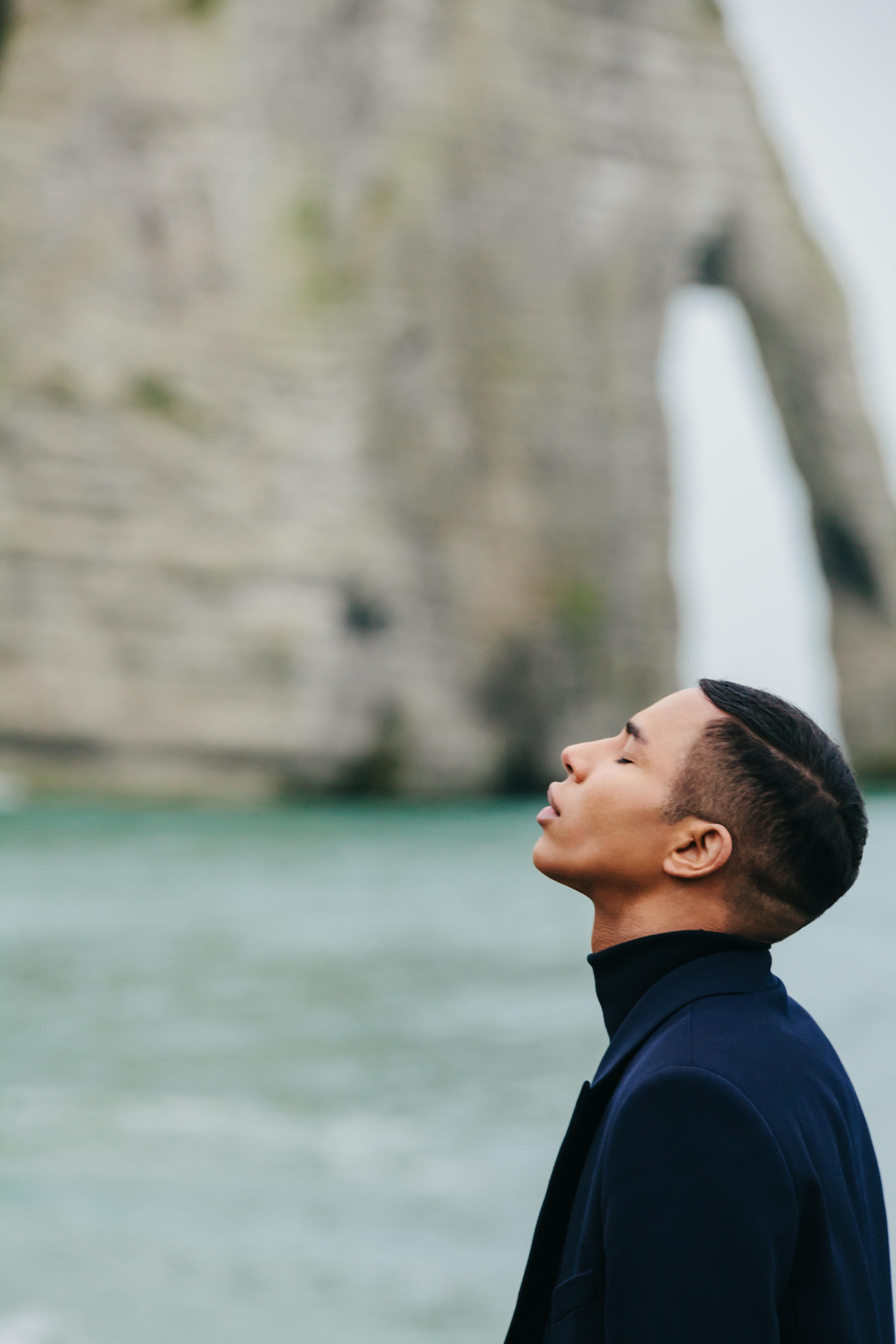 Olivier Rousteing standing on a beach, cliffs in the background