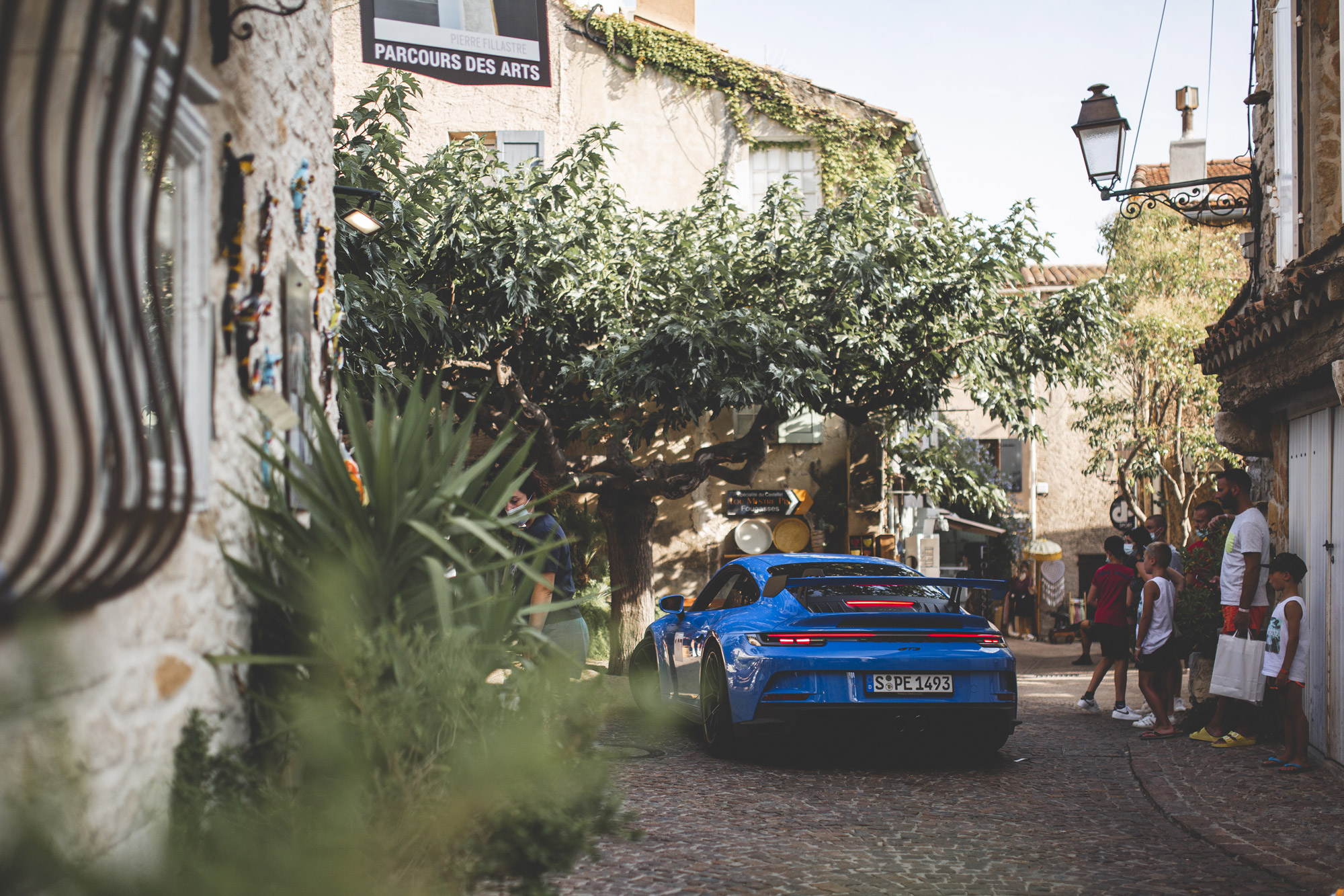 Blue Porsche 911 GT3 drives through a winding Provençal lane