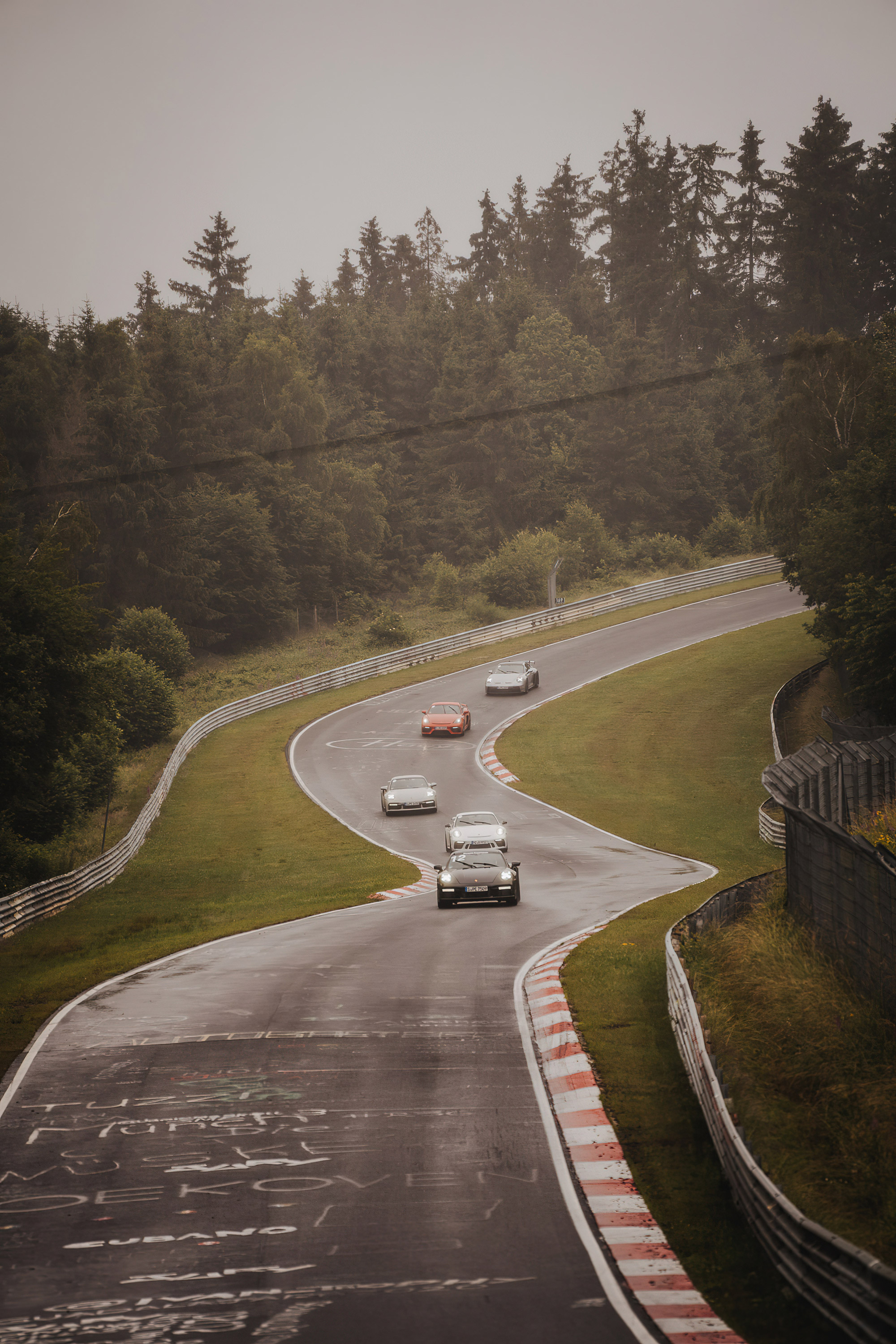 Five Porsche cars drive on the Nürburgring