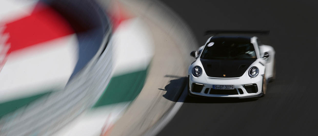 White Porsche with black hood driving on race track