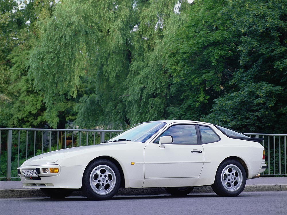 Porsche 944 parked with railing and trees behind