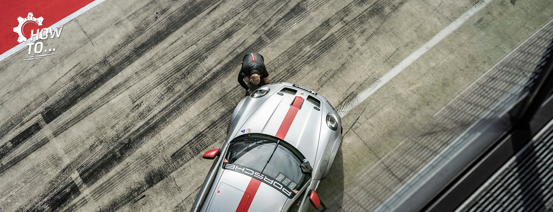 Man works on Porsche 911 GT3 racecar in pit lane