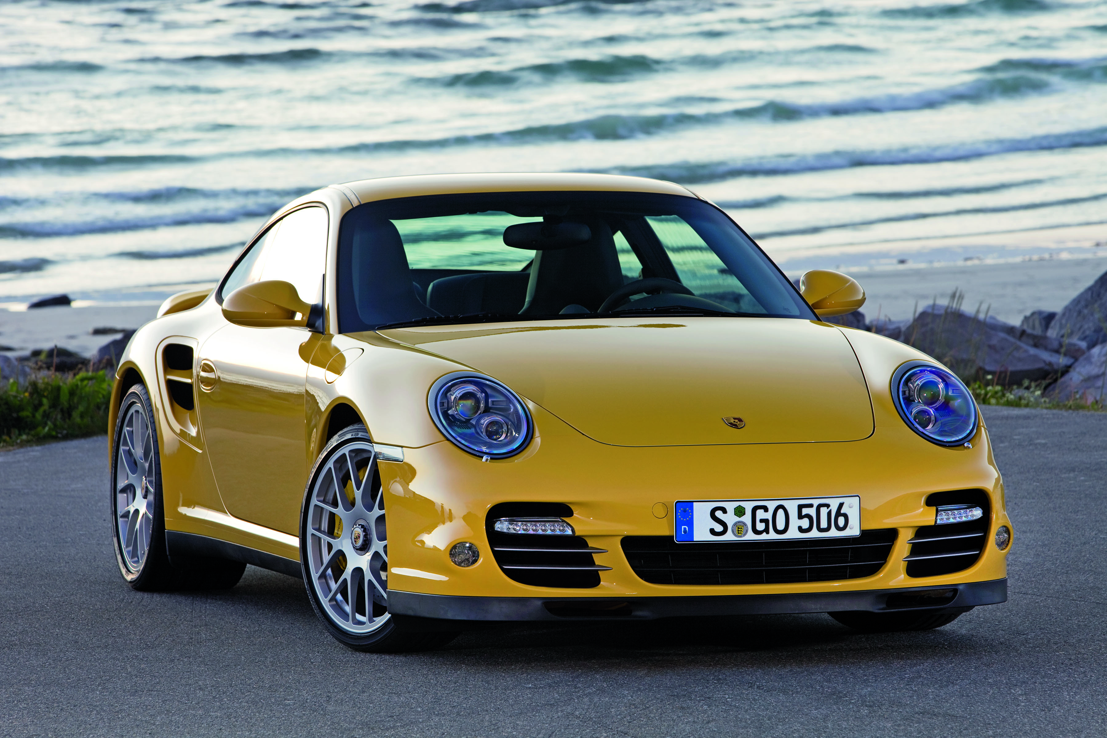 Yellow Porsche 911 Turbo parked beside the beach