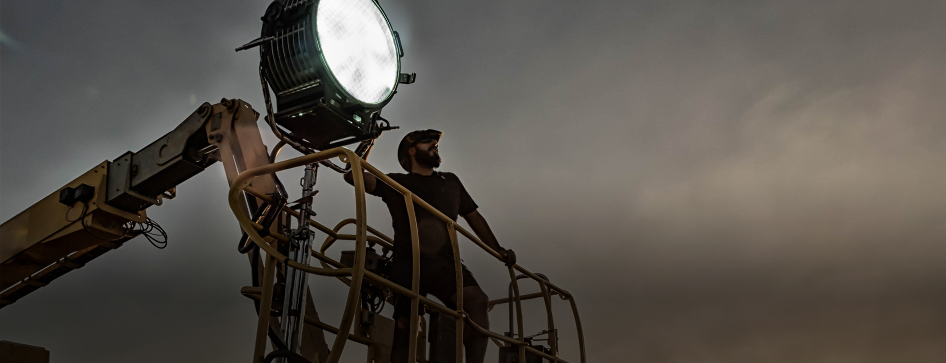 Film lighting technician on a crane in the evening light