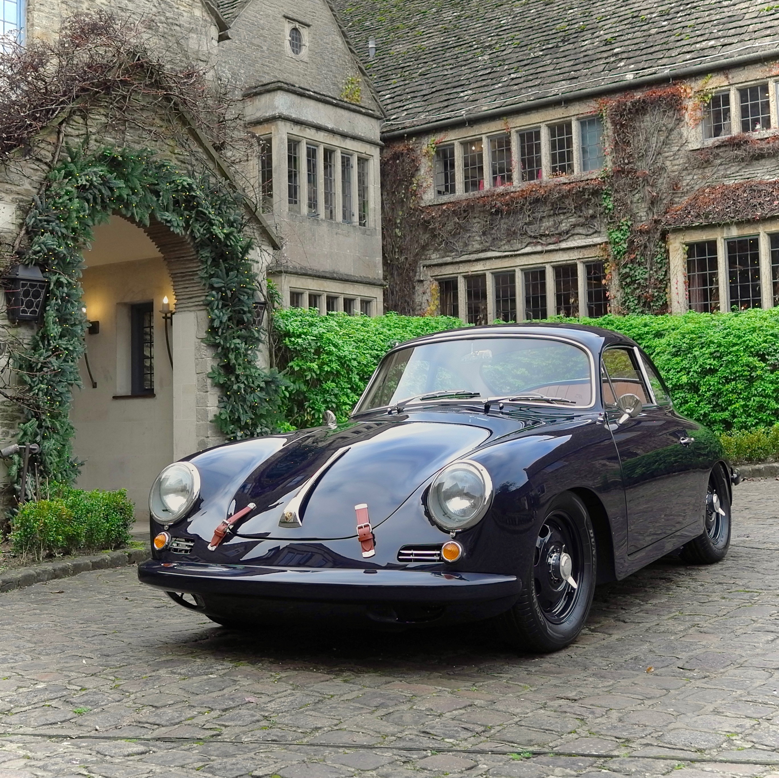 Dark blue Porsche 356 outside stone-built Cotswold country hotel