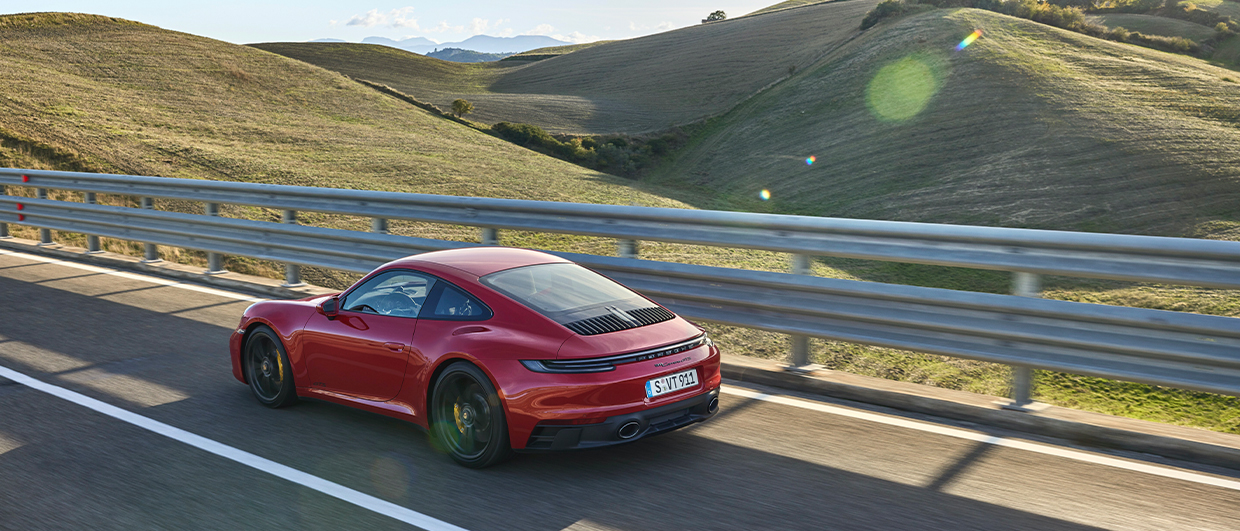 Porsche 911 Carrera GTS in Carmine Red in rolling countryside